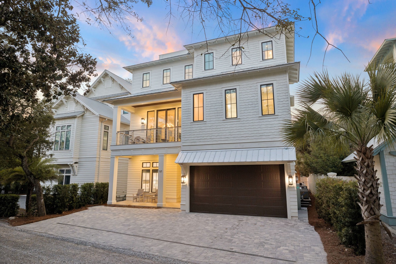 Modern coastal home with elegant architecture, featuring a spacious garage and inviting entrance surrounded by tropical landscaping.