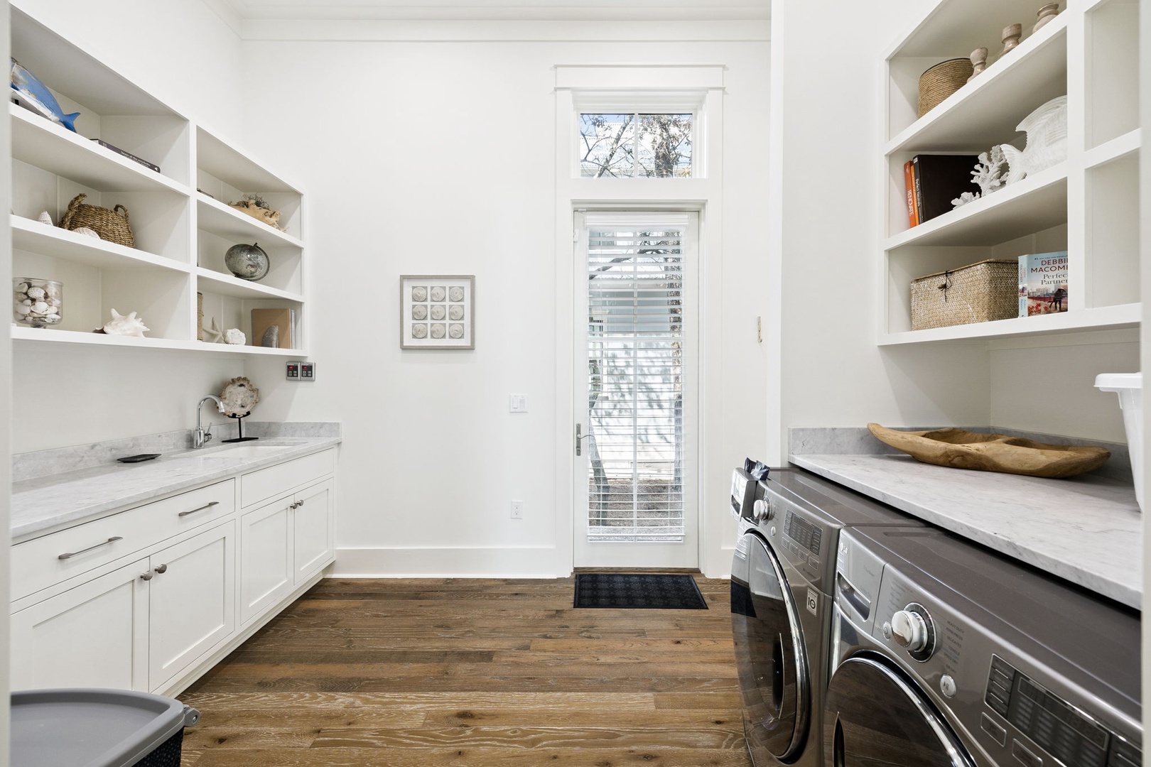 Your beautifully organized laundry room features custom white cabinetry, marble countertops, and abundant storage for all your vacation essentials.