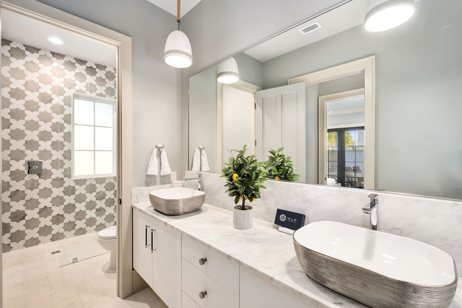 Unwind in your spa-like bathroom featuring a soaking tub, dual vanities, and elegant pendant lighting for ultimate relaxation.