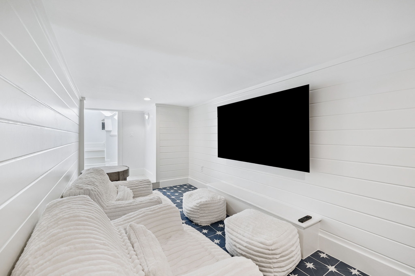 Sink into plush white seating and enjoy movie nights in your private theater room with wall-mounted TV.