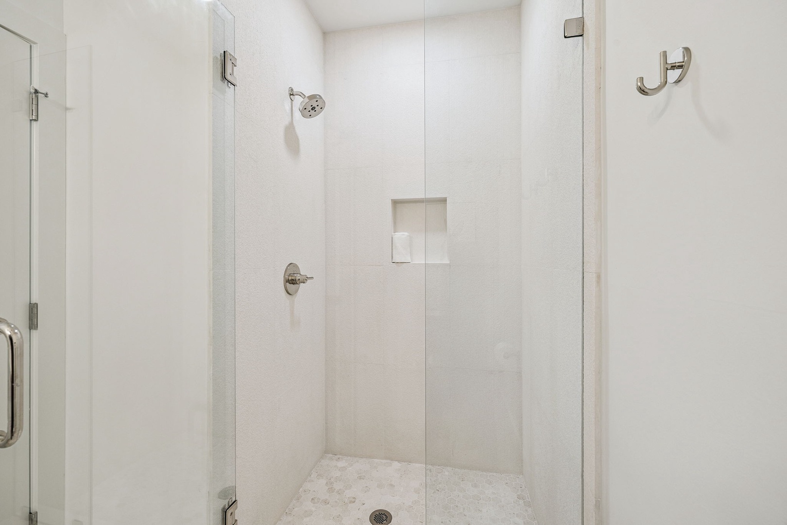 Step into your pristine glass-enclosed shower with modern fixtures and built-in niche for your toiletries.