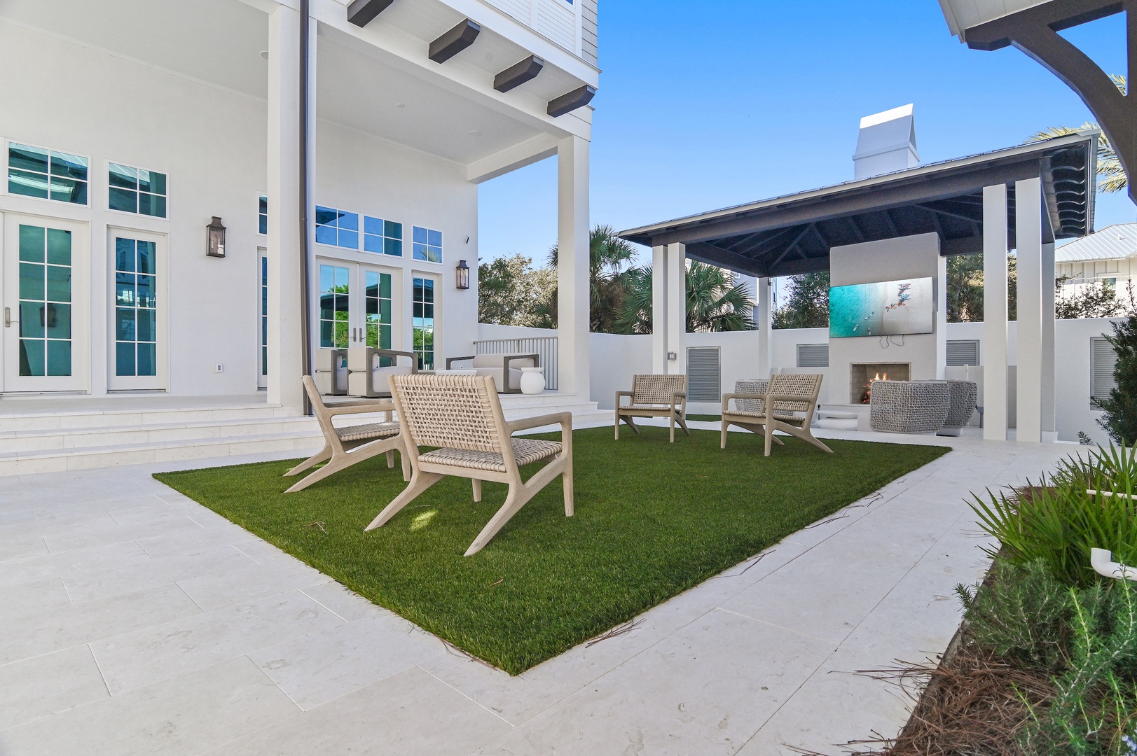 A private courtyard with modern pergolas, lush green lawn, and lounge seating creates a peaceful outdoor retreat where you can unwind, watch shows on the outdoor TV, or gather with loved ones under open skies.