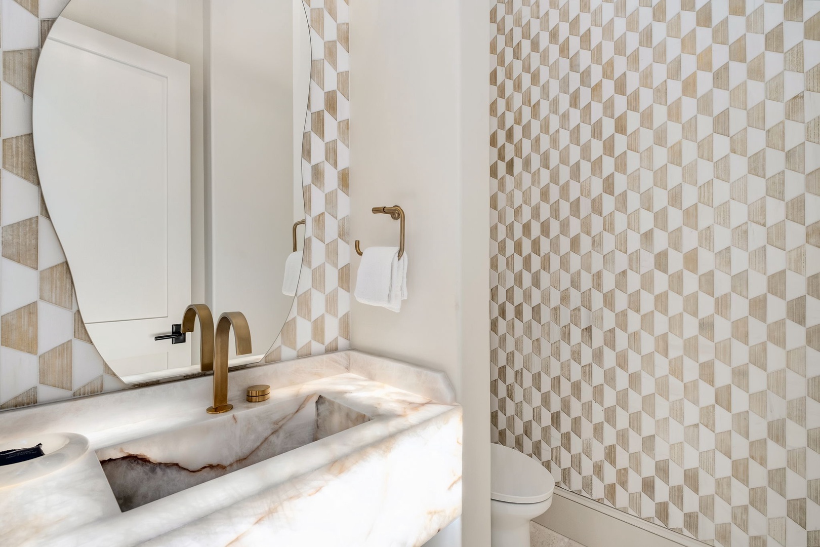 Refresh in your private bathroom featuring elegant marble countertops, designer geometric tiles, and warm brass fixtures for a luxurious touch.