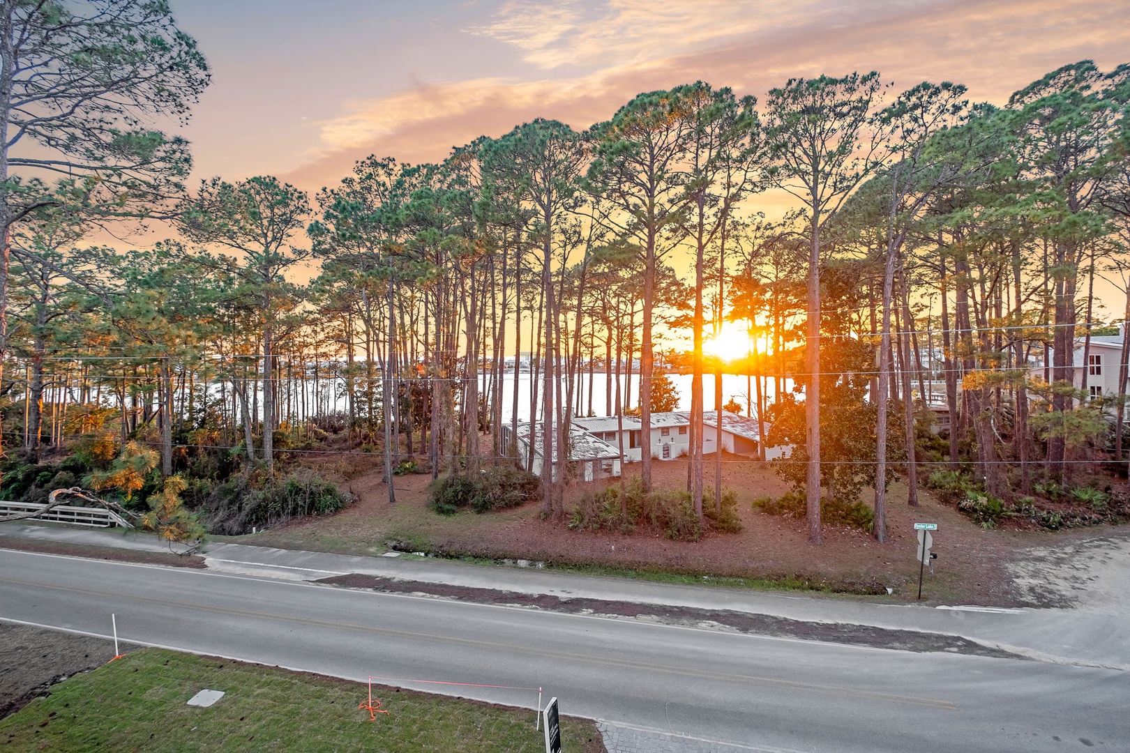 Golden sunset illuminates the tree-lined waterfront neighborhood, creating a picturesque lakeside setting for this peaceful residential area.