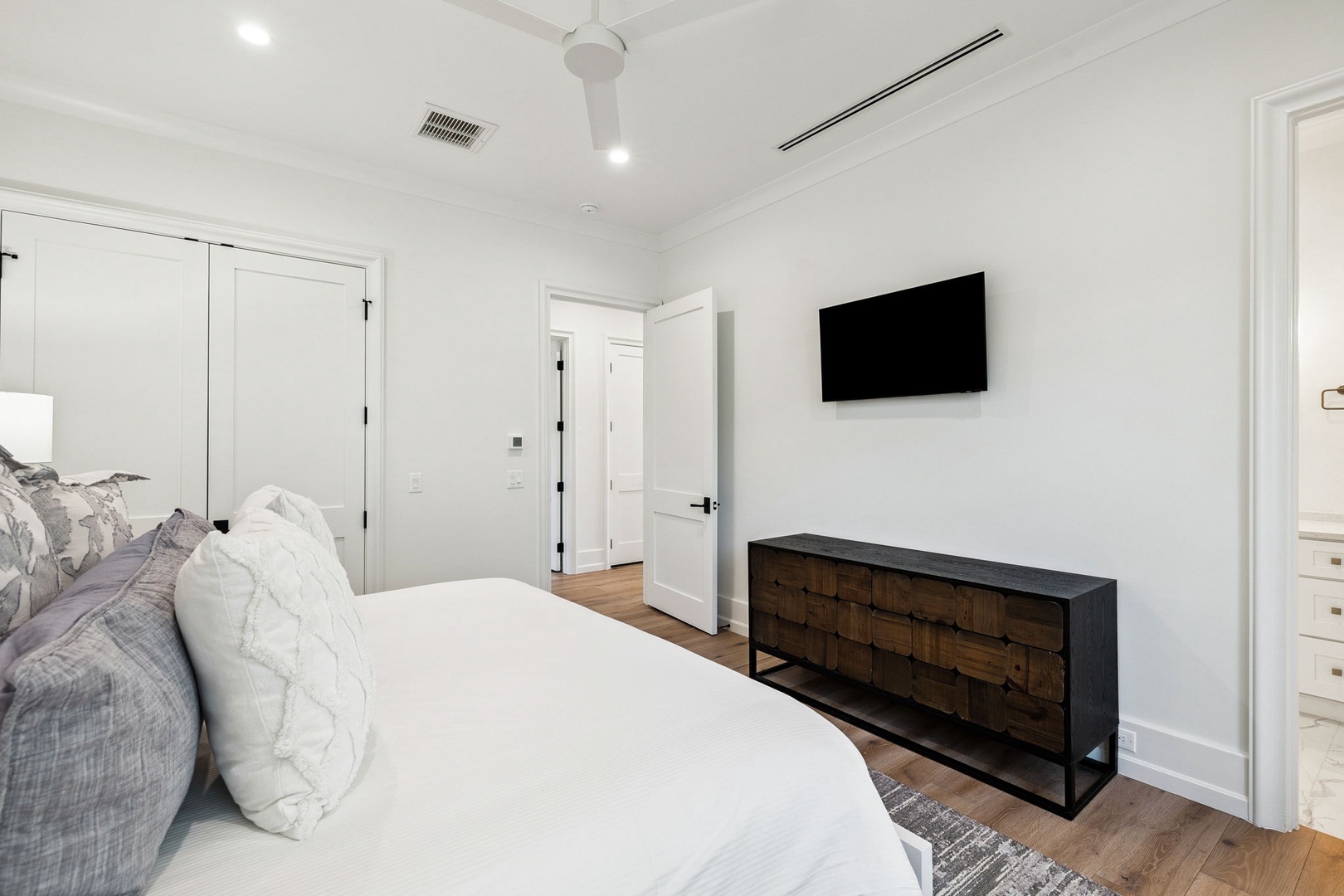 Relax in your modern bedroom with plush bedding, sleek TV, and stylish furnishings creating the perfect retreat.