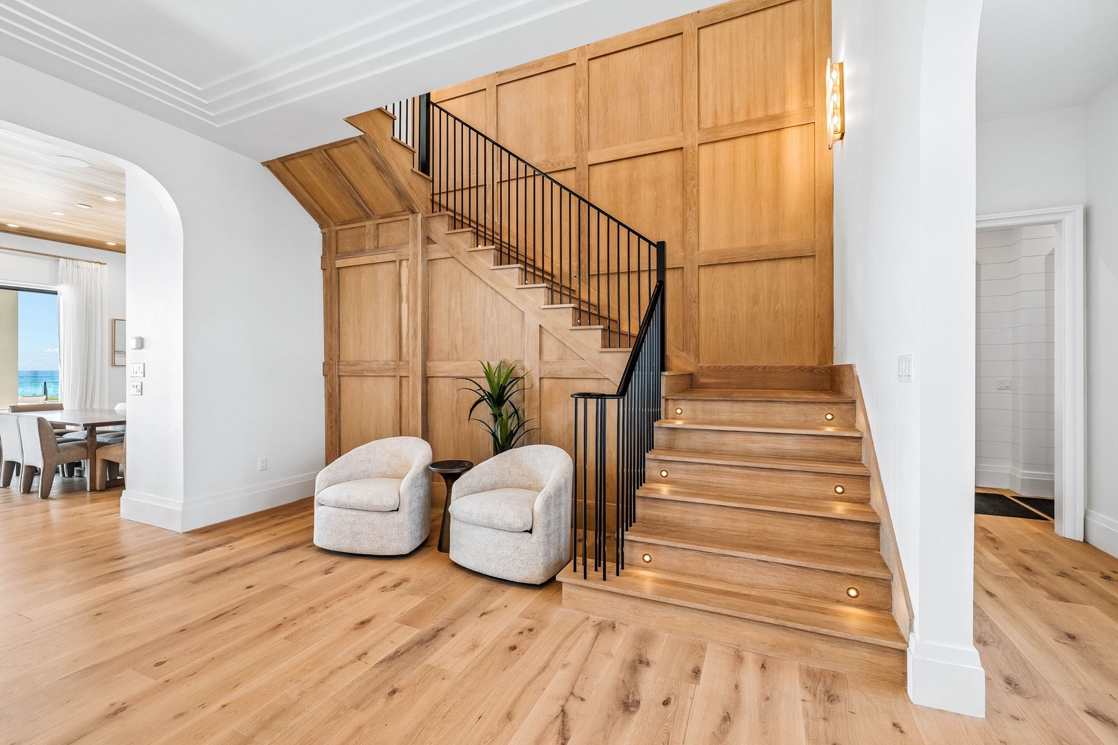 Step into your elegant two-story retreat where warm wooden staircases with modern railings set a welcoming tone. Relax in cozy seating areas and catch glimpses of the sparkling ocean beyond.