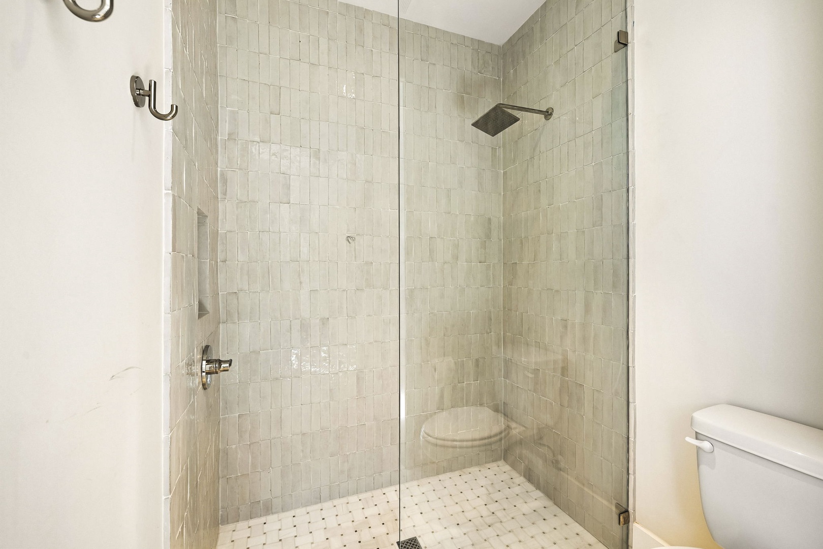 Step into your private spa-like shower featuring elegant white subway tile, a modern rain showerhead, and a spacious glass enclosure that feels bright and refreshing.