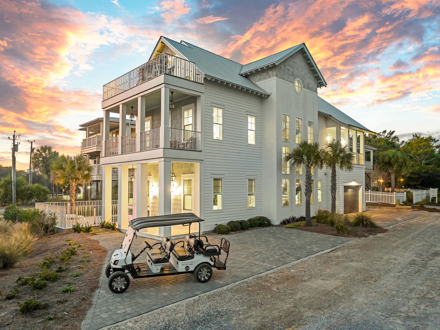Elegant coastal home with dramatic sunset sky, tropical landscaping, and convenient golf cart access in a peaceful neighborhood setting.
