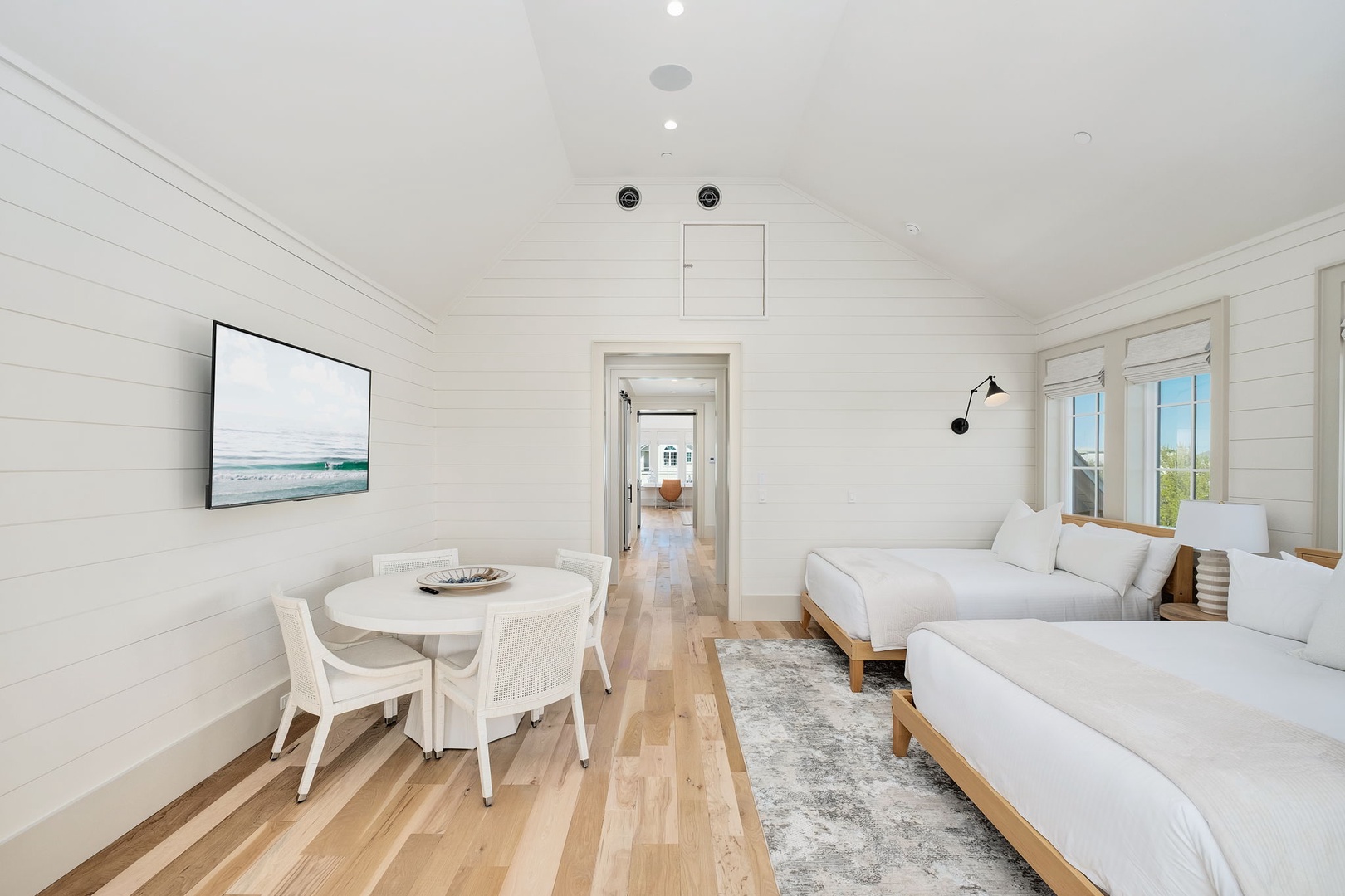 You'll love the serene white-washed walls and warm wood floors in this bright bedroom featuring twin beds and a cozy dining nook.