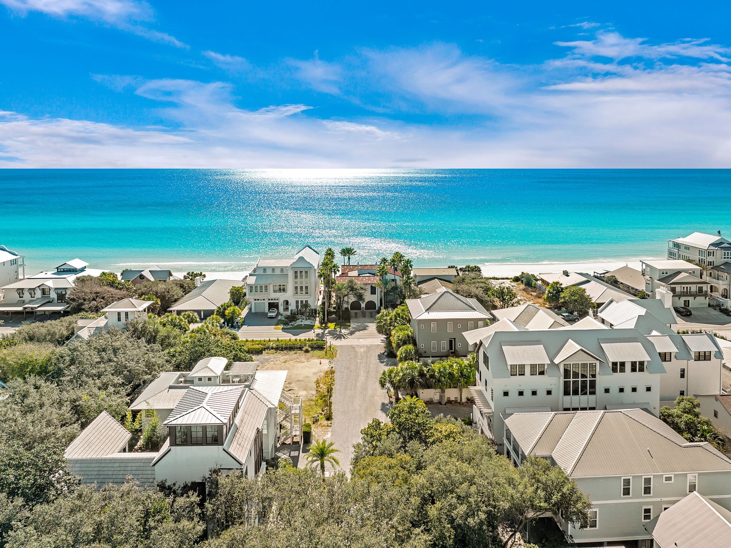 Stunning aerial view of beachfront community with pristine turquoise waters and white sand beach stretching to the horizon.