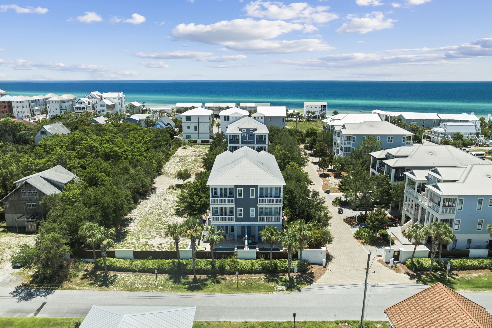 A coastal community of beach homes set among lush greenery, with pristine white sand and turquoise Gulf waters just steps away.