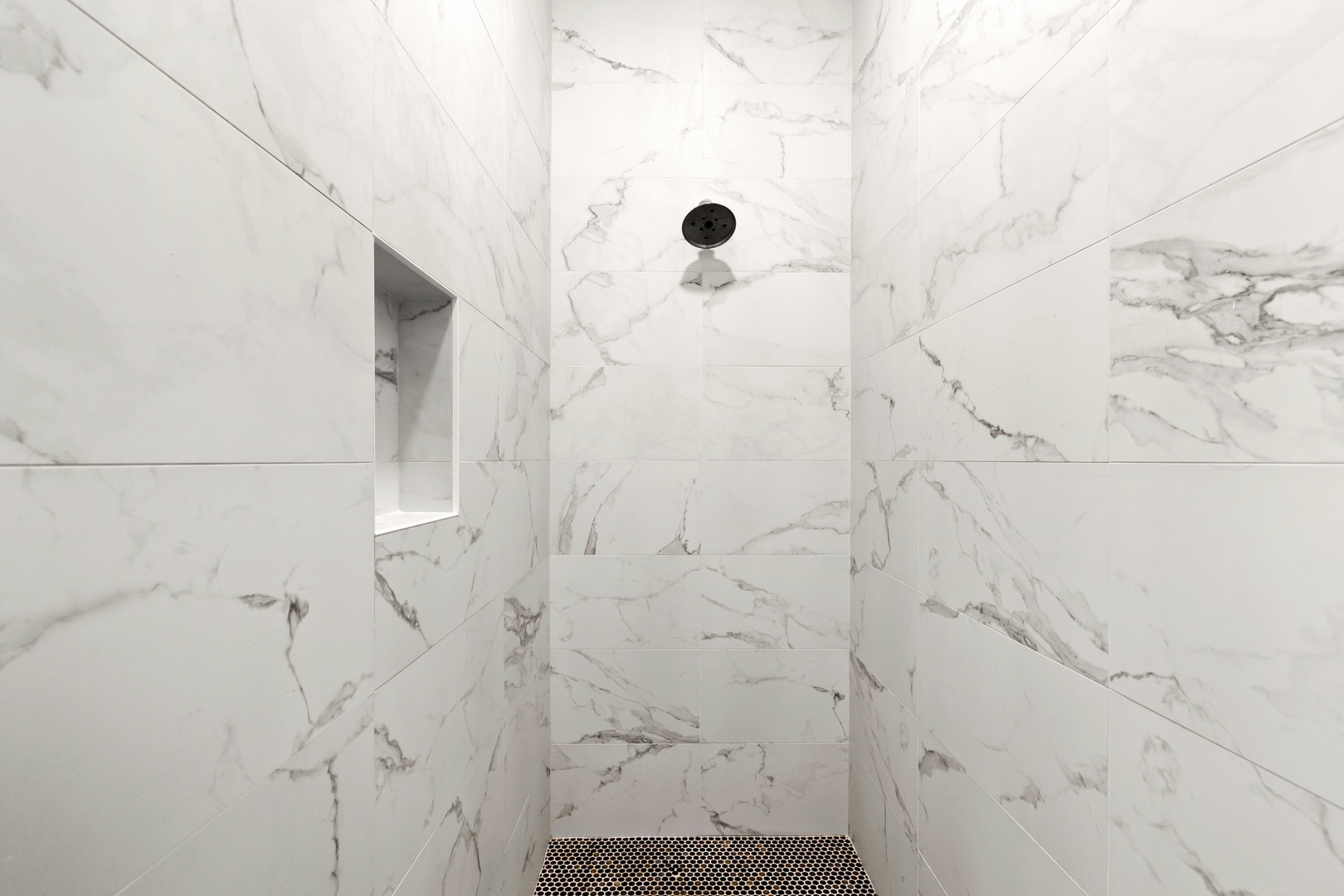 Elegant marble-tiled walk-in shower with a sleek black rainfall showerhead, offering you a spa-like experience every morning. The modern design creates a serene, luxurious retreat for your daily refresh.