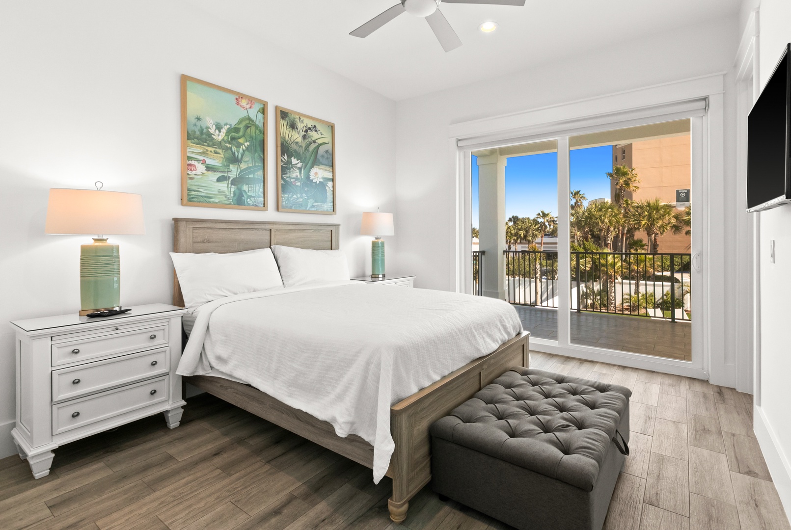 Your peaceful coastal bedroom awaits with soft linens, gentle ceiling fan breezes, and a private balcony opening to swaying palms and blue sky.