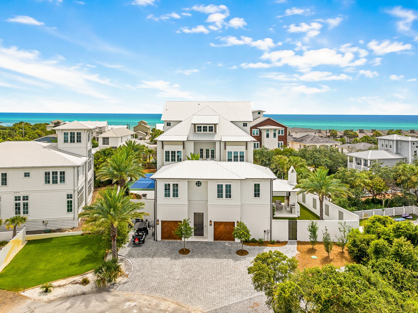 Modern coastal property nestled in a vibrant beachside community, surrounded by lush palms and tropical landscaping, with the turquoise Gulf waters just beyond.