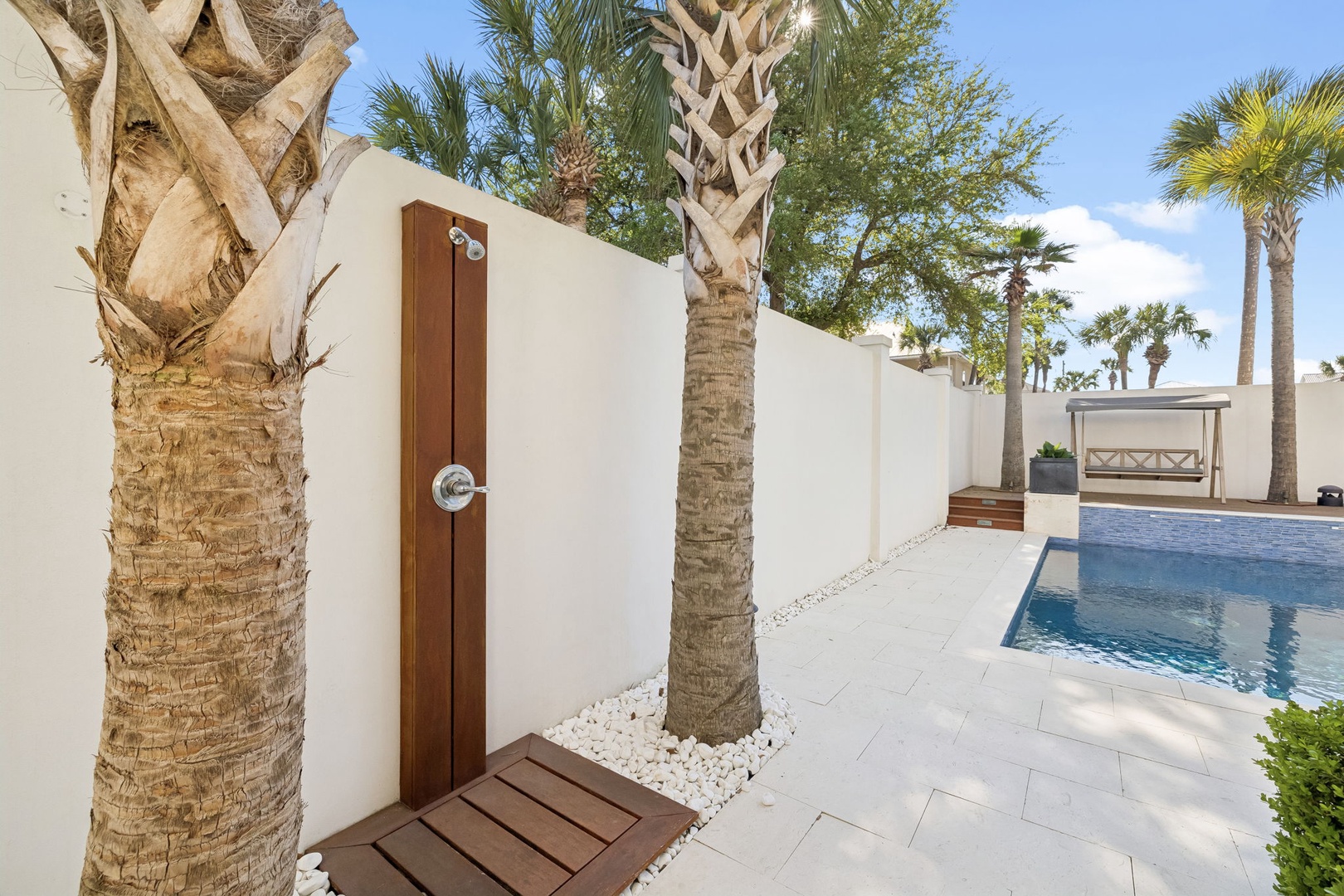 Step into your private outdoor oasis where a sleek shower awaits among swaying palms.