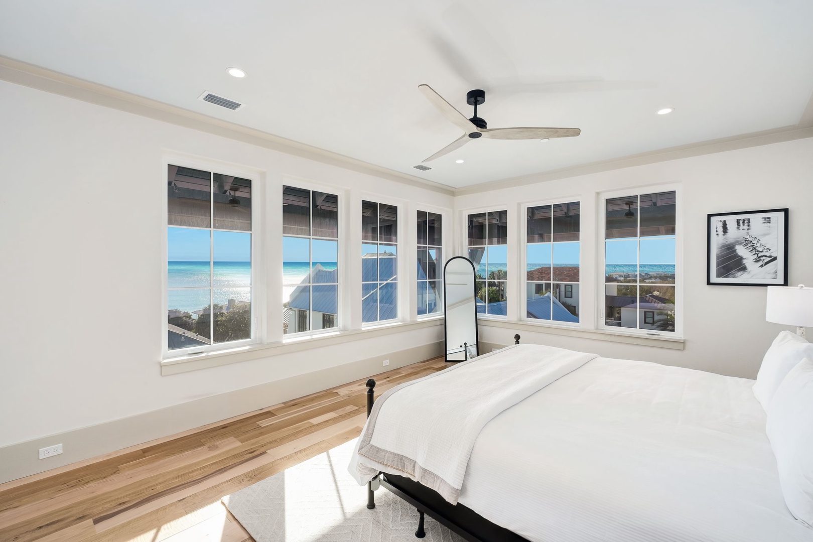 Wake up to stunning ocean views through floor-to-ceiling windows that wrap around your bright, airy bedroom with luxurious linens and coastal charm.