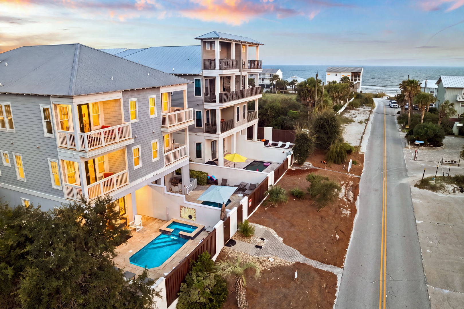 A stunning beachfront property nestled in a serene coastal neighborhood, featuring a private pool and multiple balconies overlooking the ocean, just steps from sandy shores.