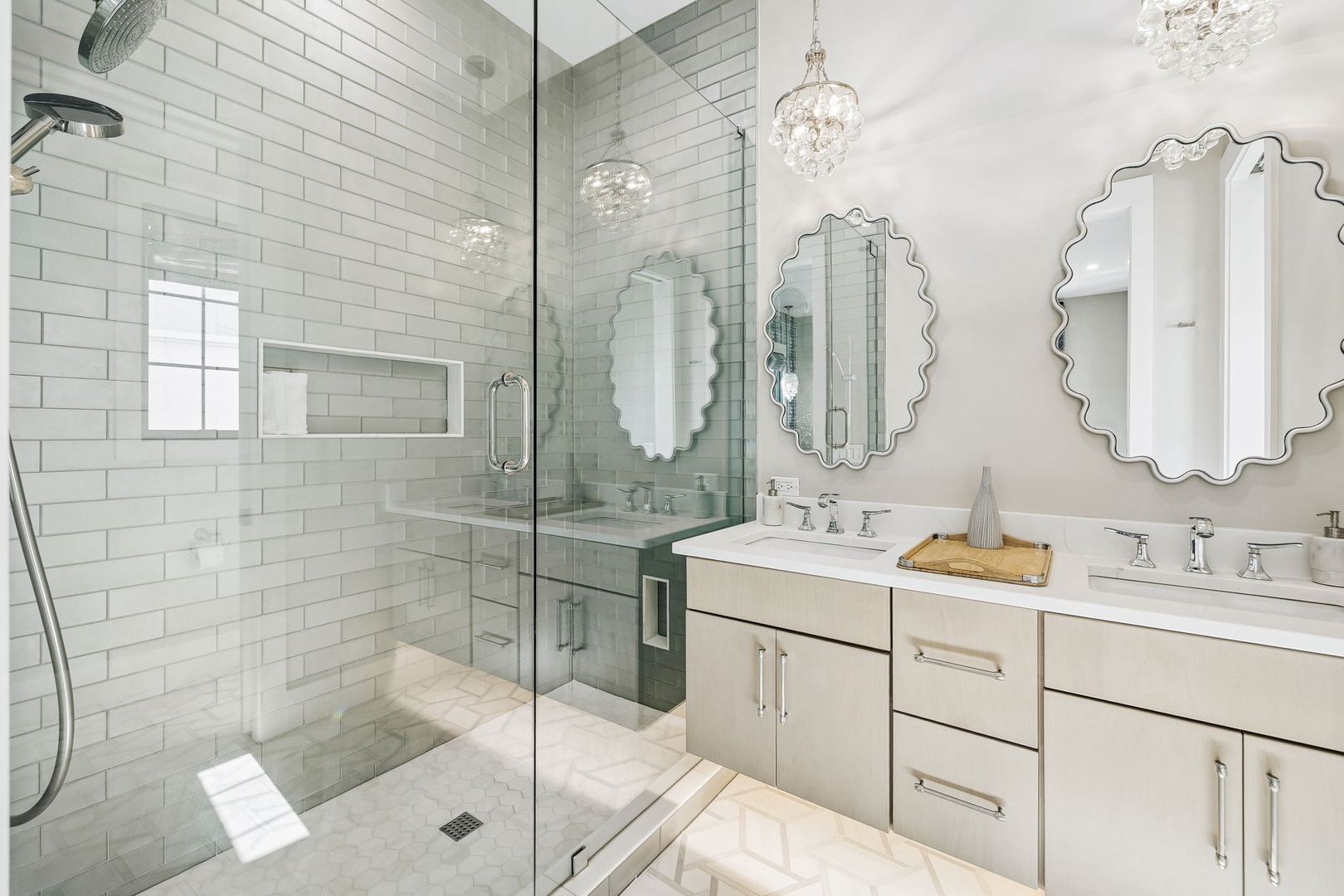 Indulge in spa-like luxury with gleaming white subway tile, a spacious walk-in shower, and elegant crystal chandeliers that add a touch of glamour to your daily routine.