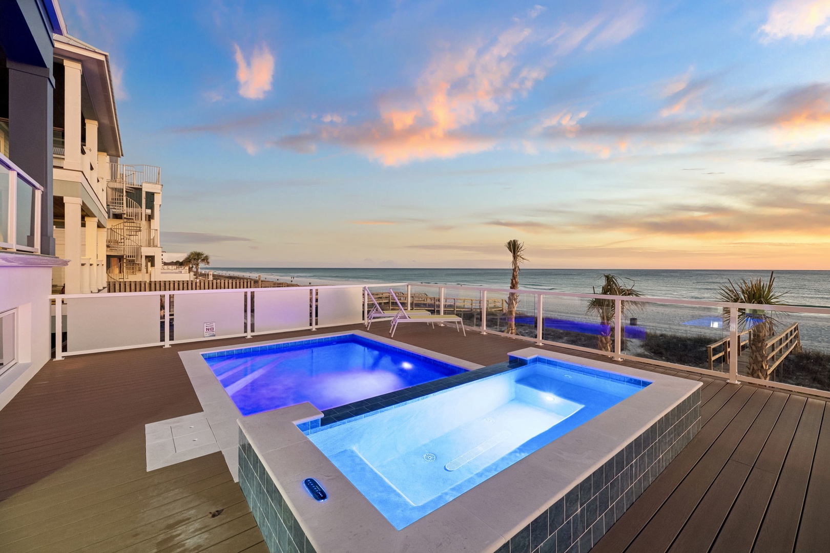 Beachfront property featuring oceanfront pool and hot tub with stunning sunset views over the water.