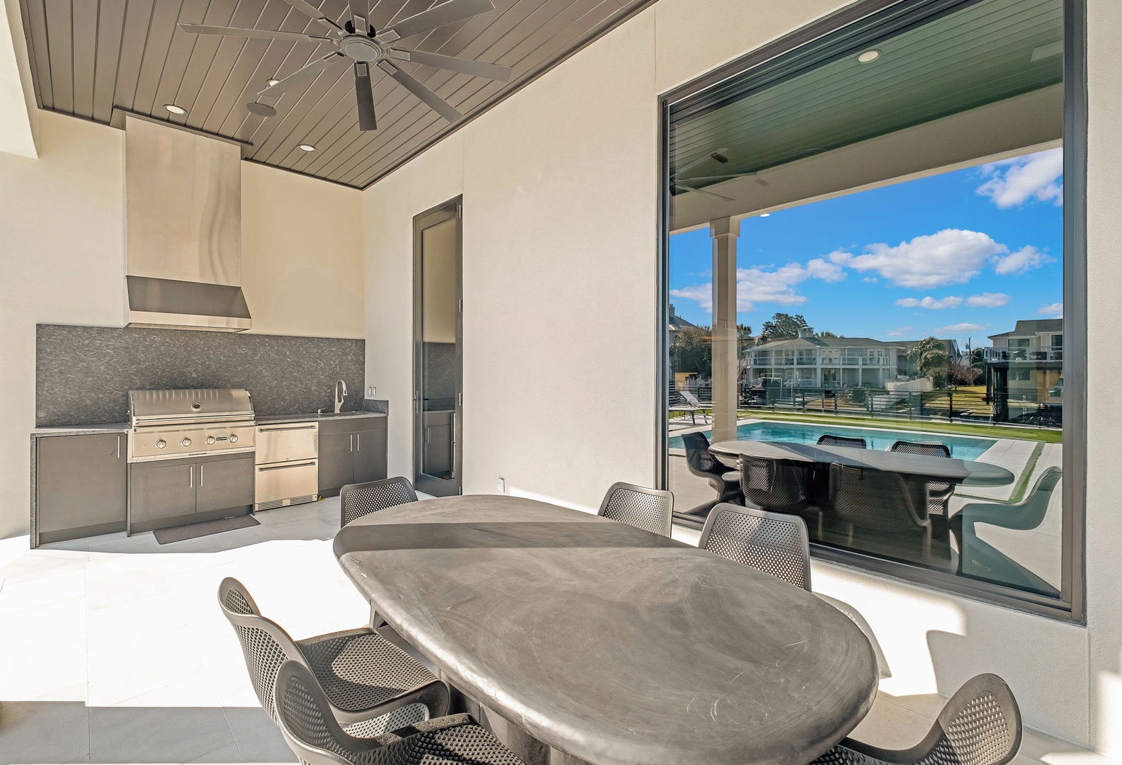 Your modern outdoor kitchen and dining space opens to the sparkling pool, perfect for memorable meals with fresh air and sunshine.