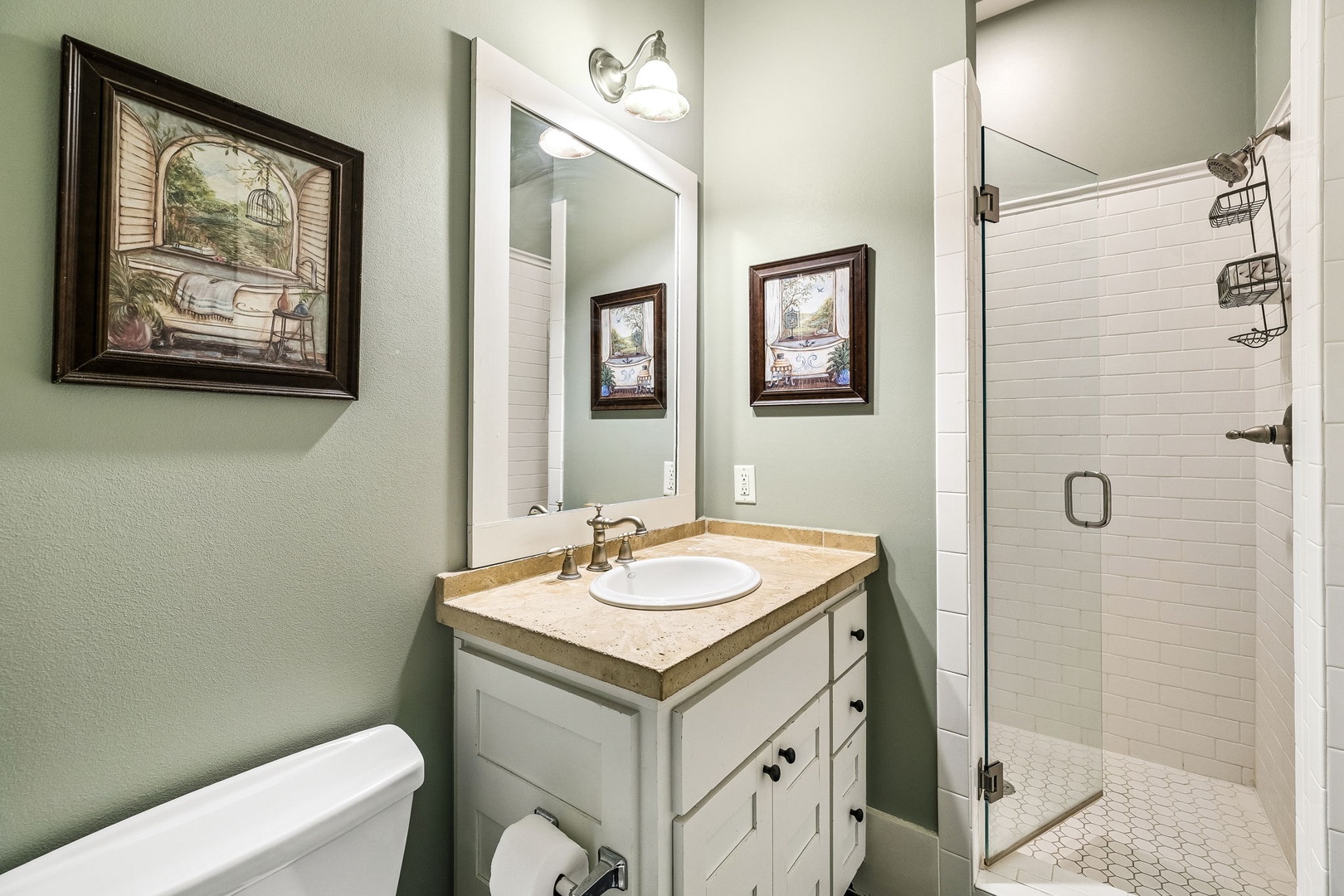 Your private bathroom features a walk-in shower with subway tile, a vanity with warm stone countertops, and thoughtful touches like framed art and soft lighting to make getting ready feel like a treat.