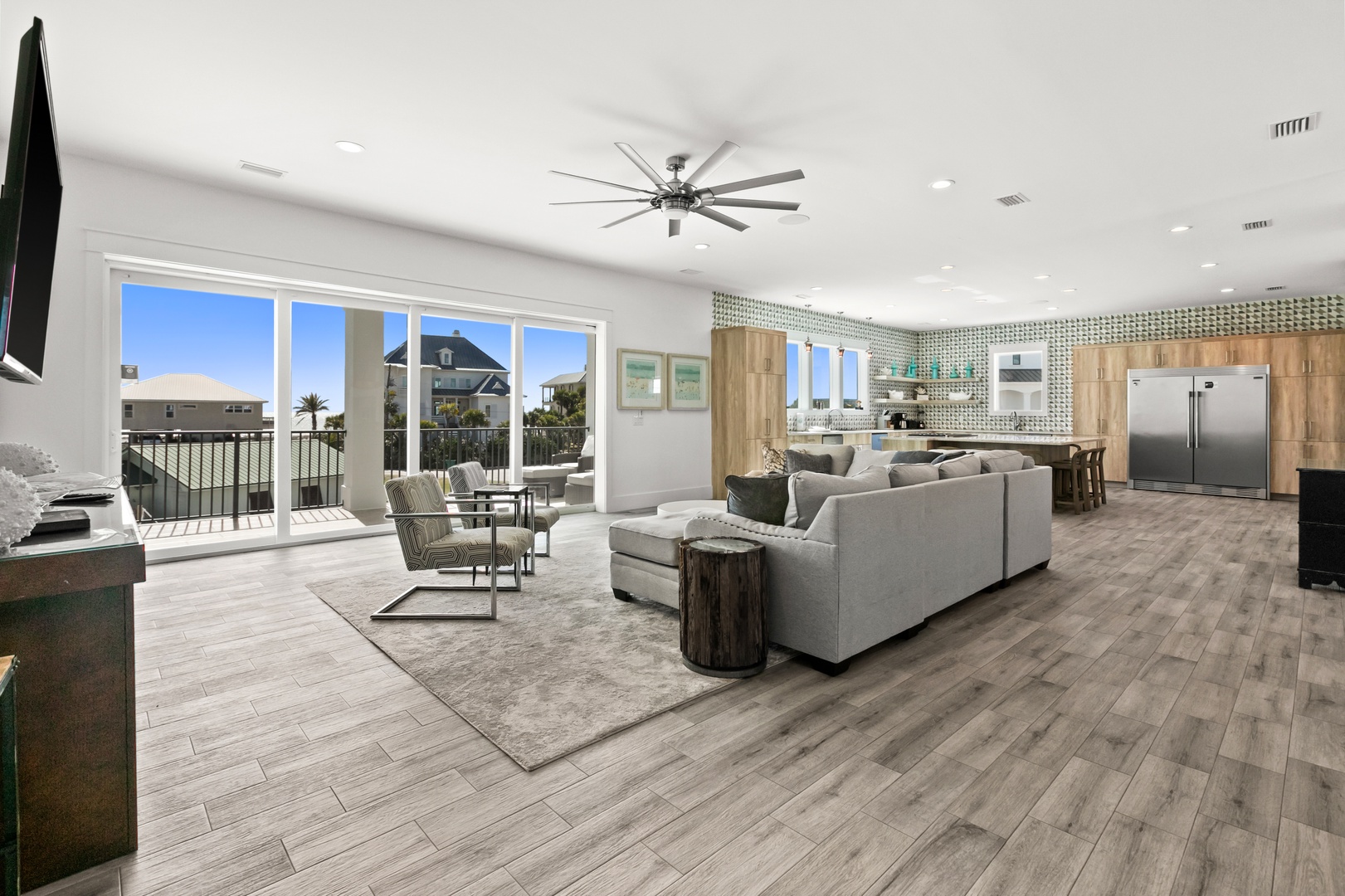 Step into this bright, open living space where modern comfort meets relaxed style. Sink into the plush sectional, enjoy the ocean breeze through sliding glass doors, and gather with loved ones in a room designed for easy, memorable moments.