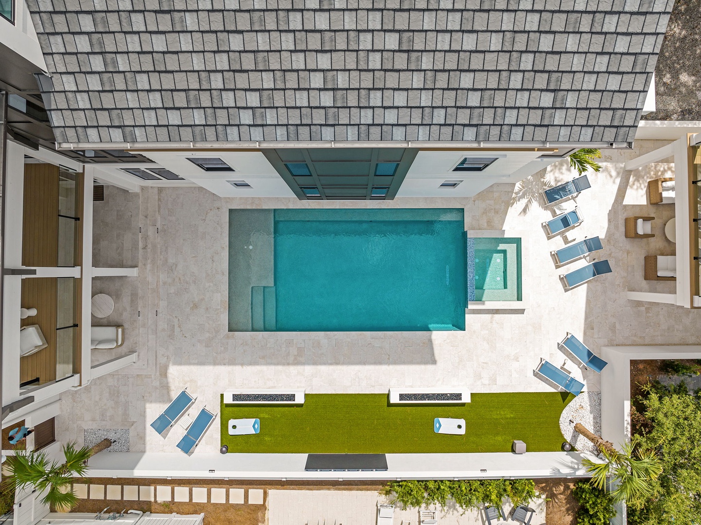An aerial view showcasing the property's pool area surrounded by modern outdoor spaces and verdant greenery.