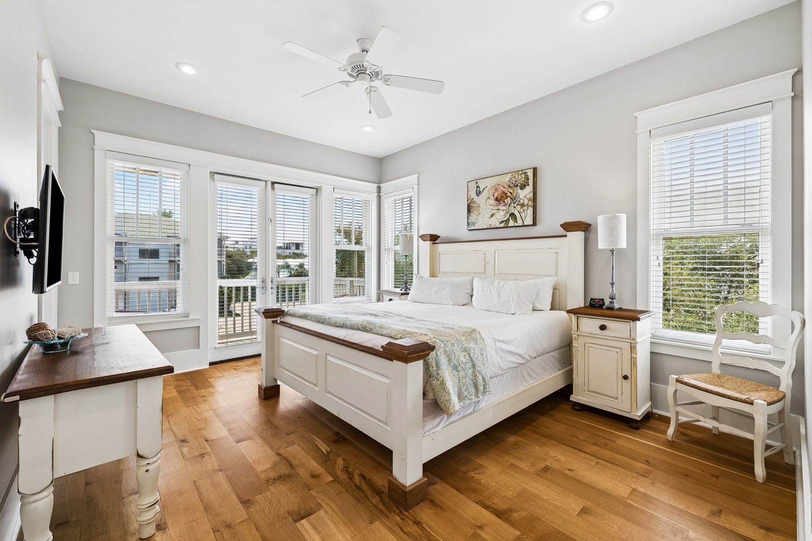 Sink into crisp white linens and natural light in your charming bedroom, where warm wood floors and peaceful water views welcome you home.