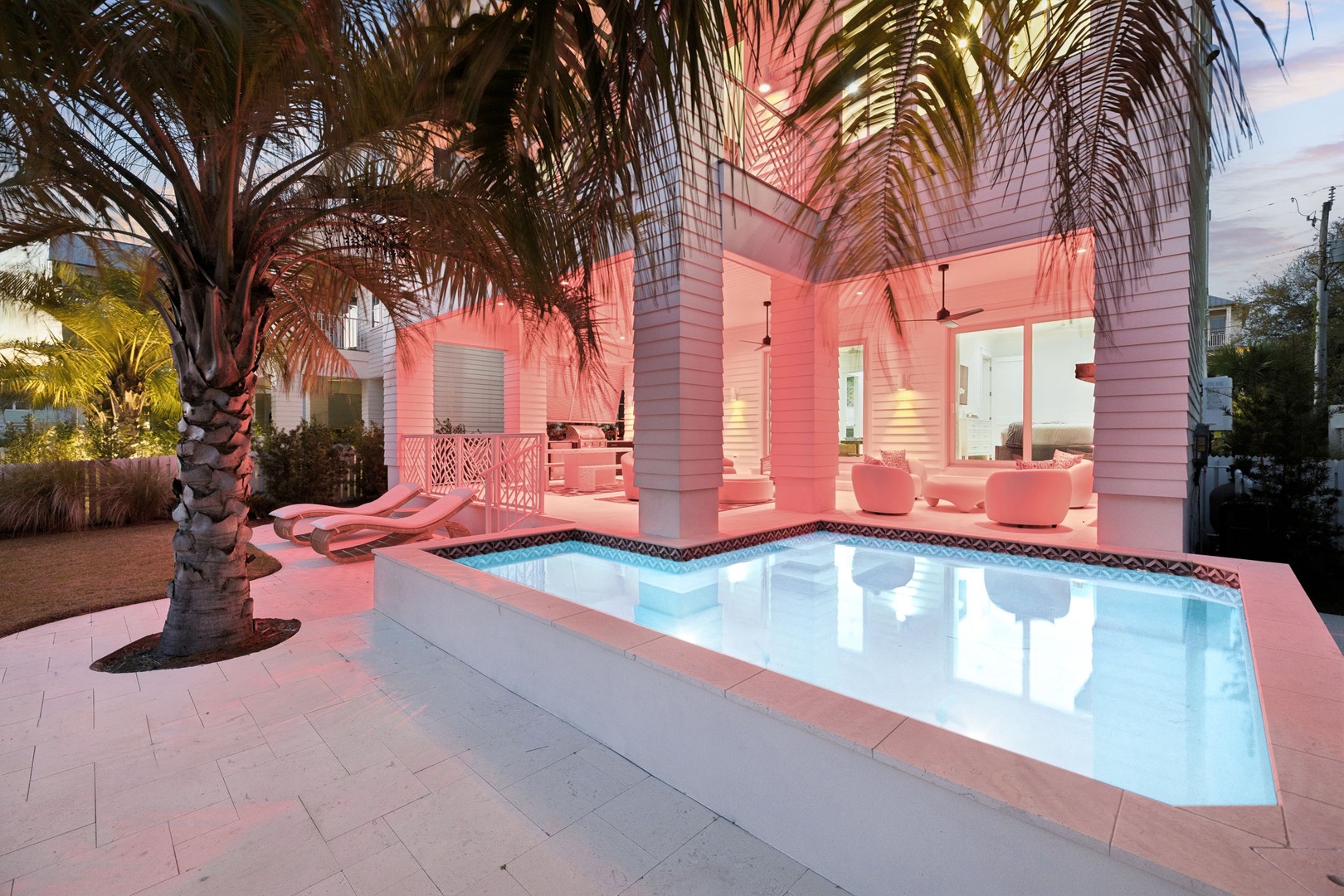 Your private pool glows under warm tropical lighting, framed by swaying palms and elegant poolside seating for ultimate relaxation.
