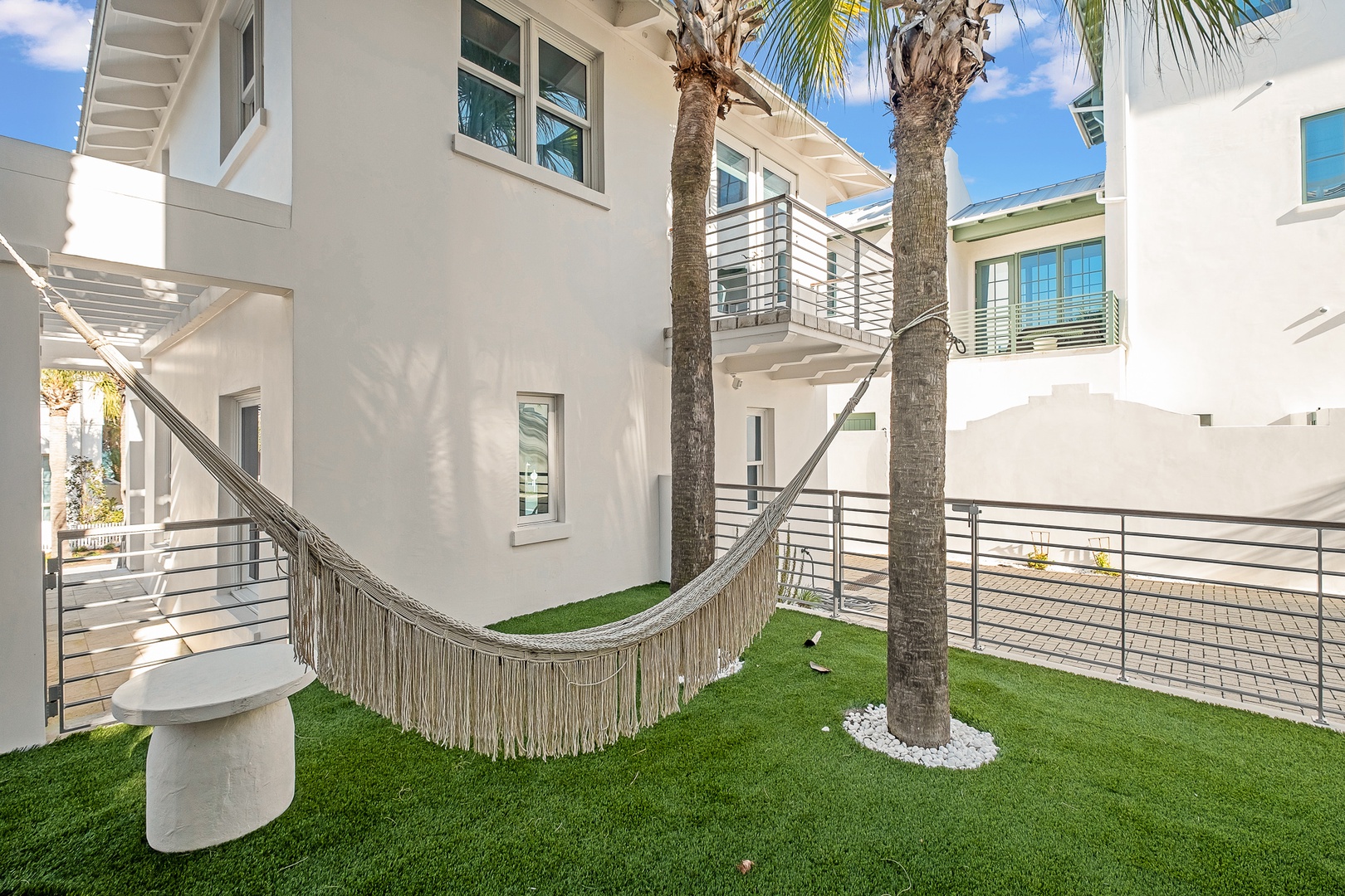 Swing gently in your private hammock beneath swaying palms, where tropical relaxation meets modern comfort in this sun-drenched courtyard oasis.