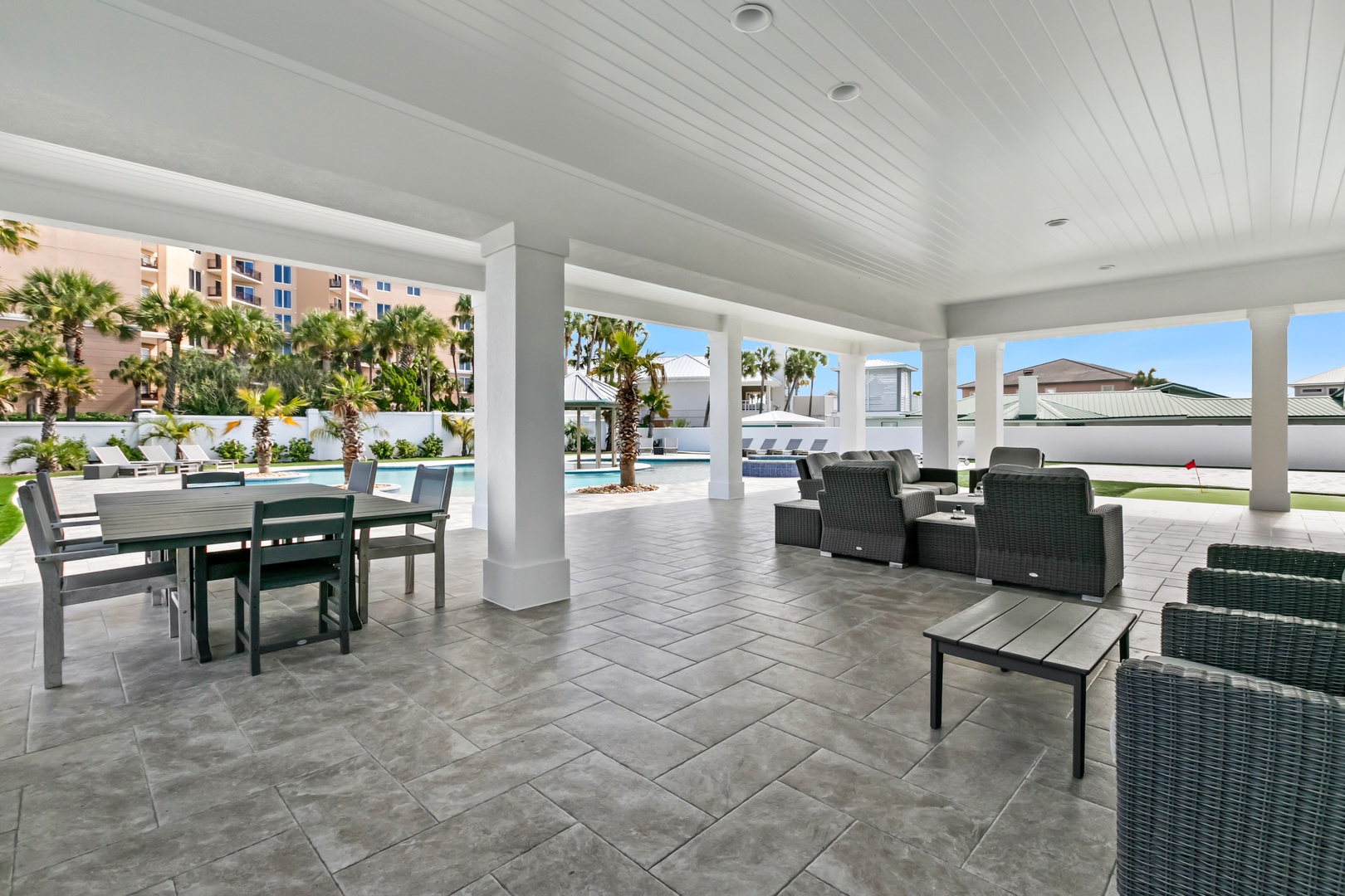 Gather under the covered patio with comfortable seating and dining space, perfect for sunny mornings or cool evenings by the pool.