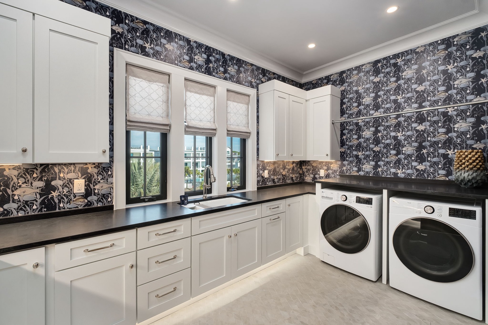 Your laundry routine becomes a luxurious experience in this stunning space with elegant botanical wallpaper, ample counter space, and premium appliances.