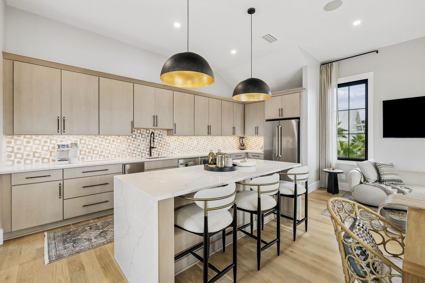 Picture yourself gathering around this sleek marble island, sunlight streaming through the windows, as you sip morning coffee or prep a meal in your bright, modern kitchen with warm pendant lighting overhead.