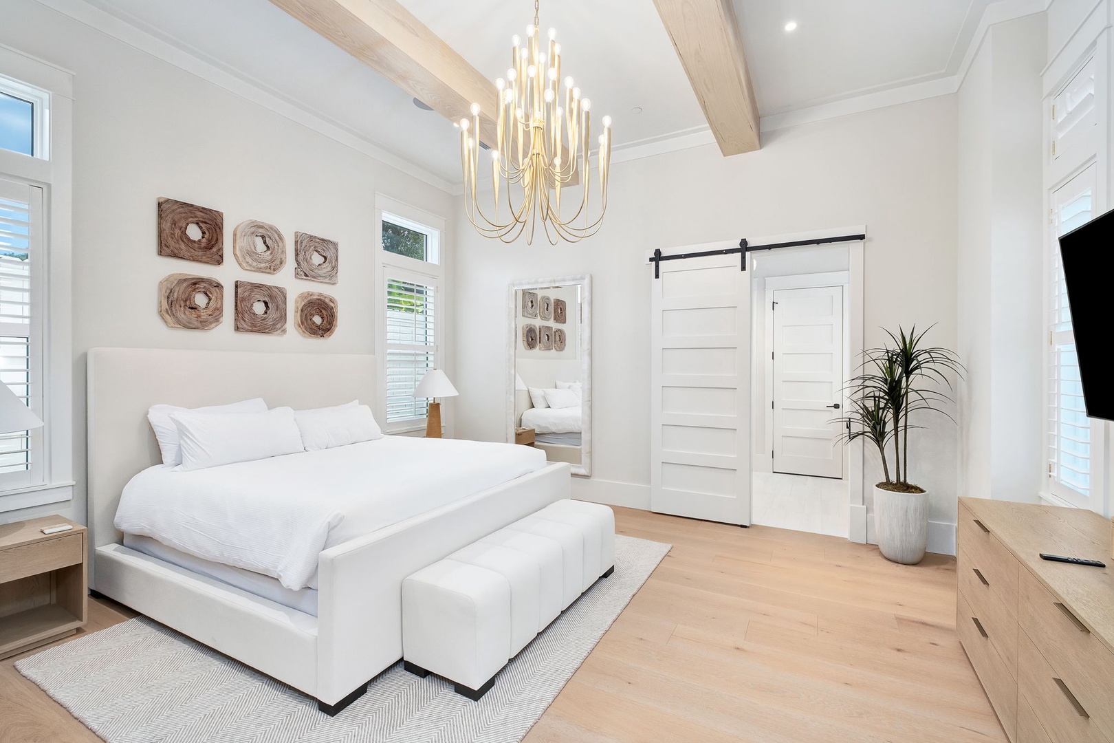 Step into your serene primary suite, where vaulted ceilings, natural wood accents, and soft white linens create a peaceful coastal retreat just for you.