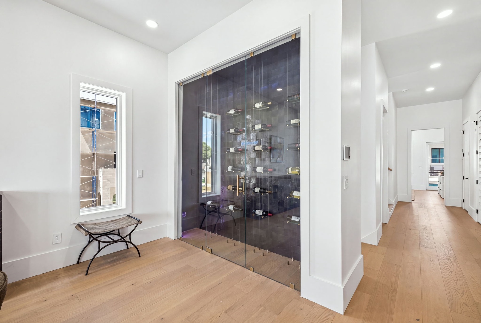 Step into bright, modern elegance with gleaming hardwood floors underfoot and a sleek, climate-controlled glass-enclosed wine display that makes every bottle a centerpiece.