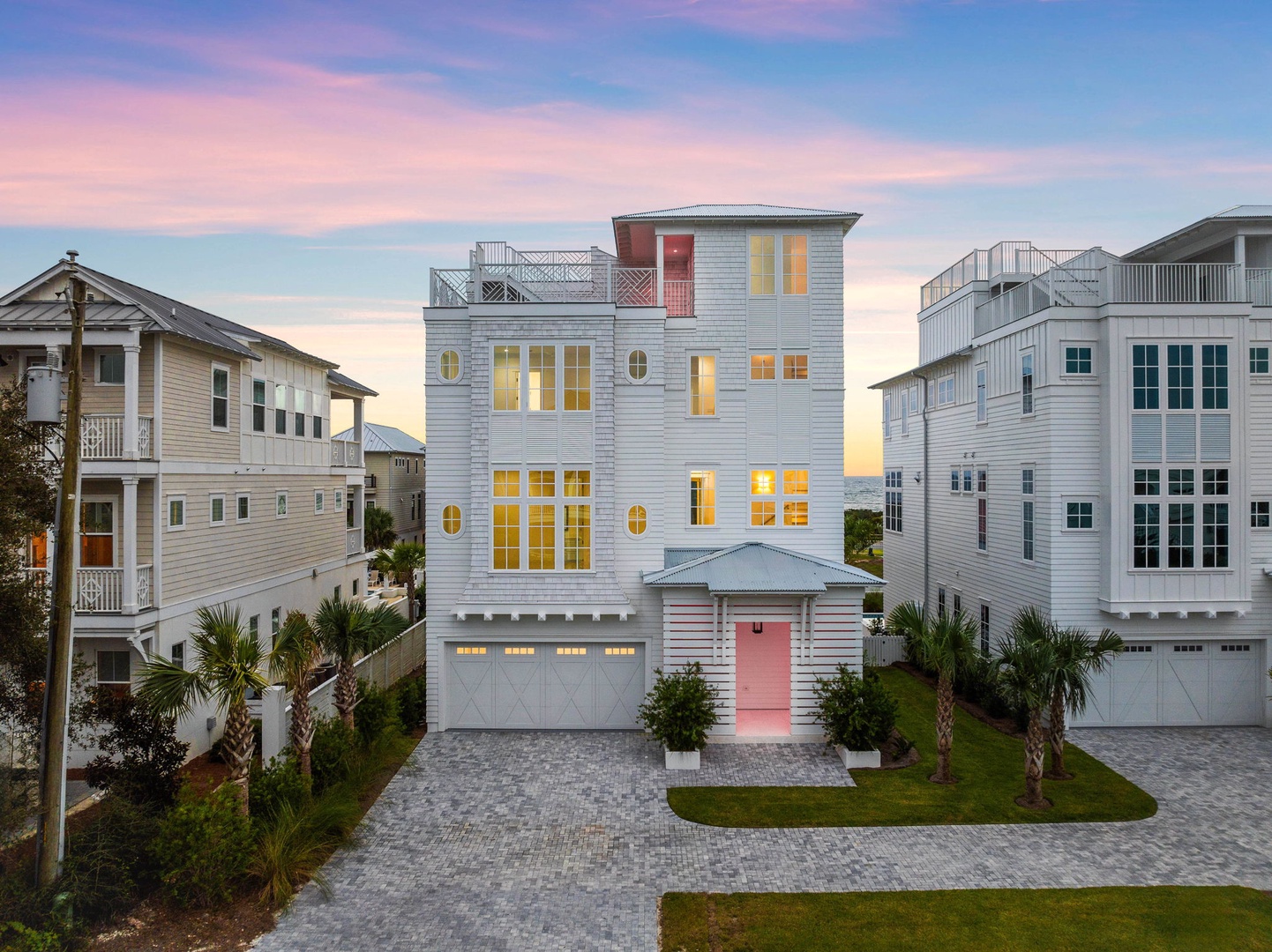 Modern coastal home with elegant architecture nestled among similar properties in a stylish neighborhood during golden hour.