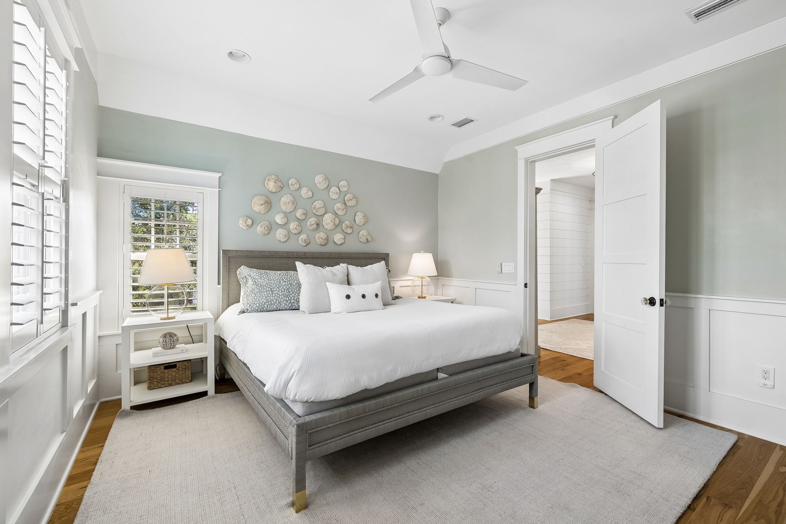 Slip into soft linens and let the calming coastal hues ease you into relaxation—your peaceful retreat awaits beneath the gentle ceiling fan.