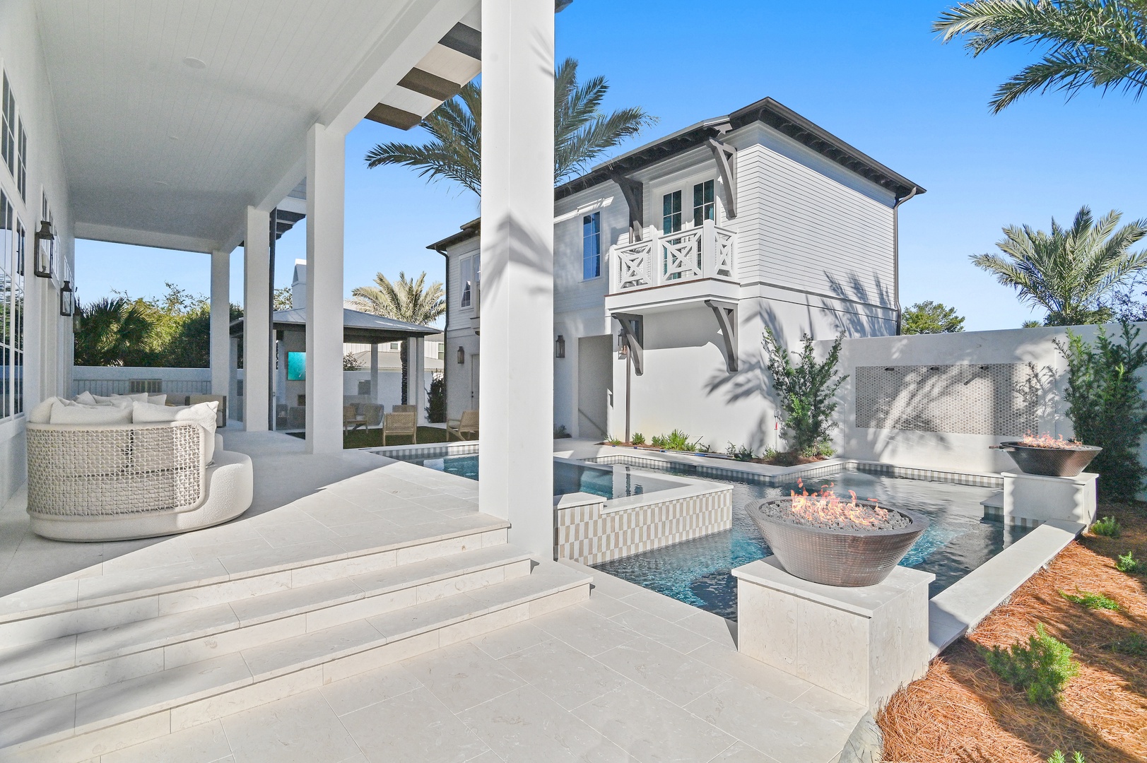 This stunning property features a private pool with elegant fire bowls, a covered patio with comfortable seating, and beautiful palm trees creating your own tropical retreat.