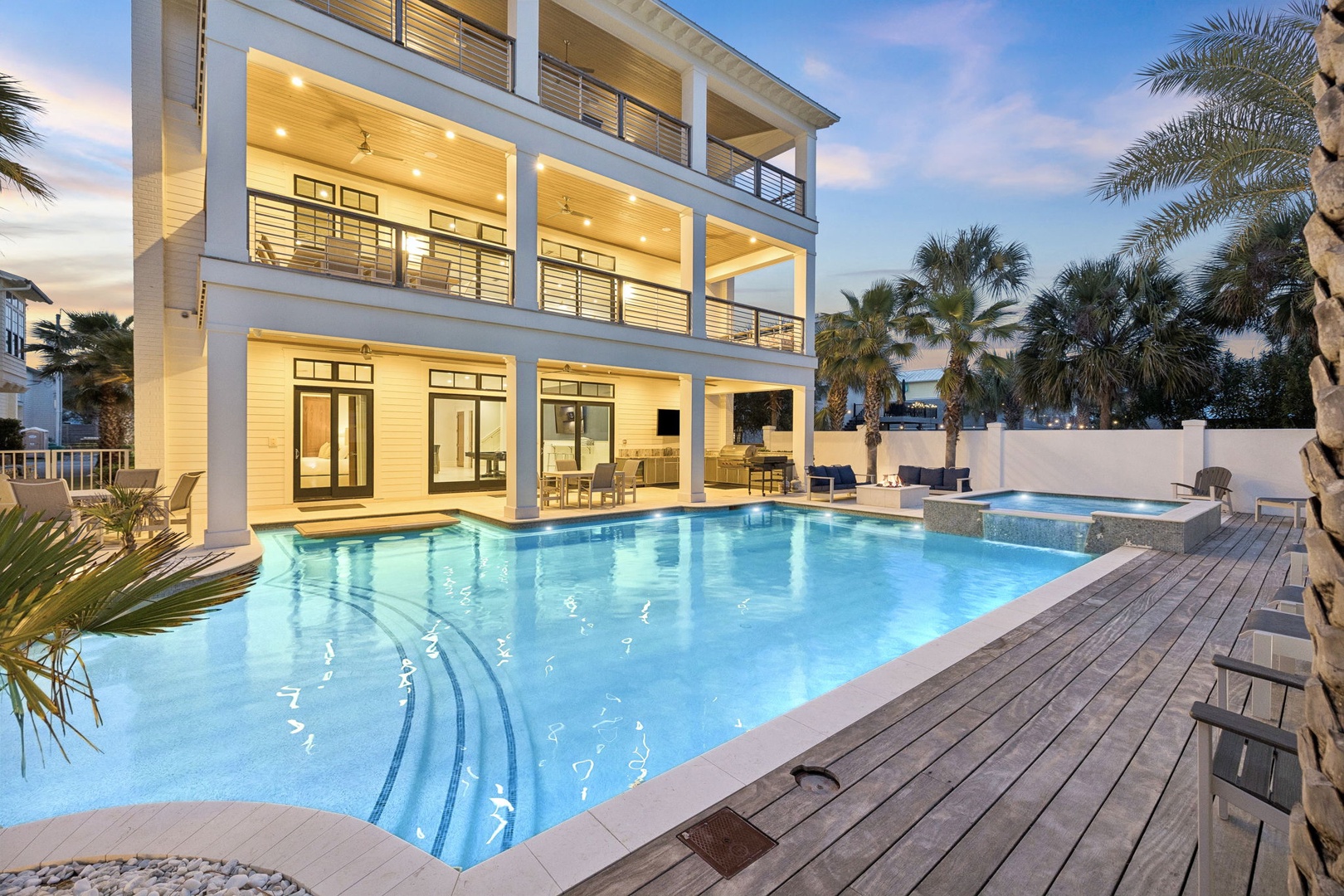 Modern three-story vacation home with pristine swimming pool, tropical landscaping, and elegant outdoor entertainment areas in an upscale residential setting.
