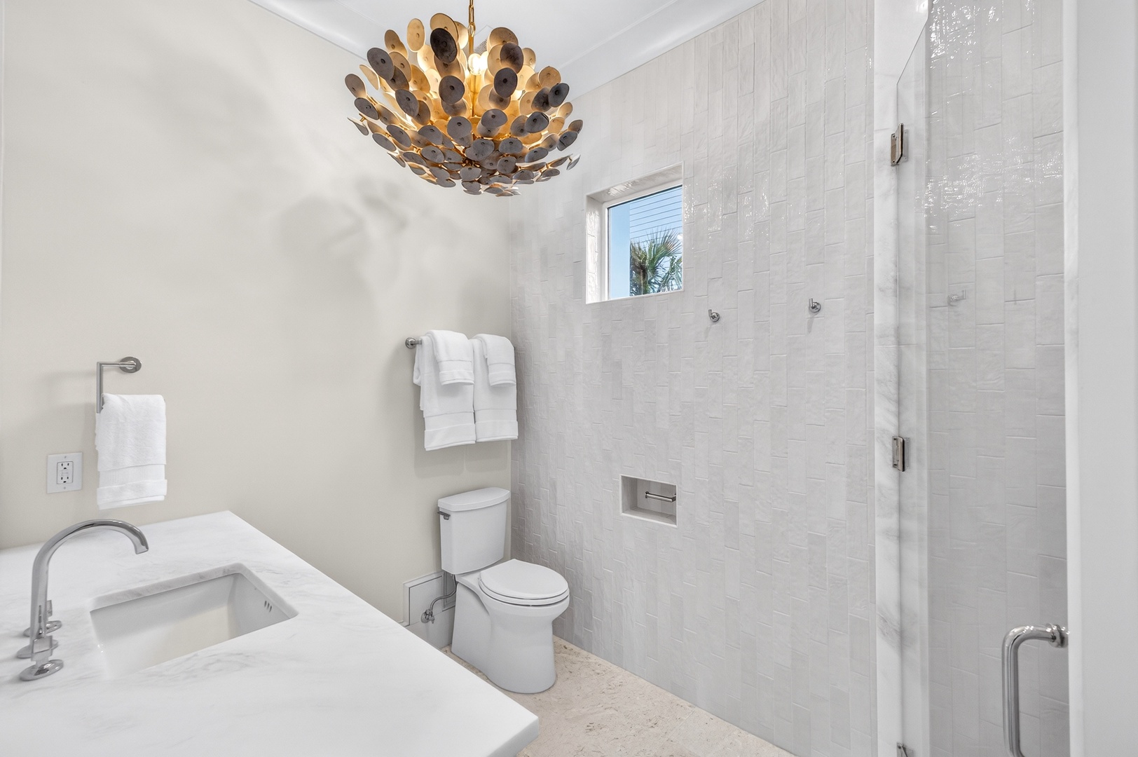 Your private bathroom sparkles with elegant marble tile and a stunning statement chandelier, creating a spa-like retreat for your daily routine.
