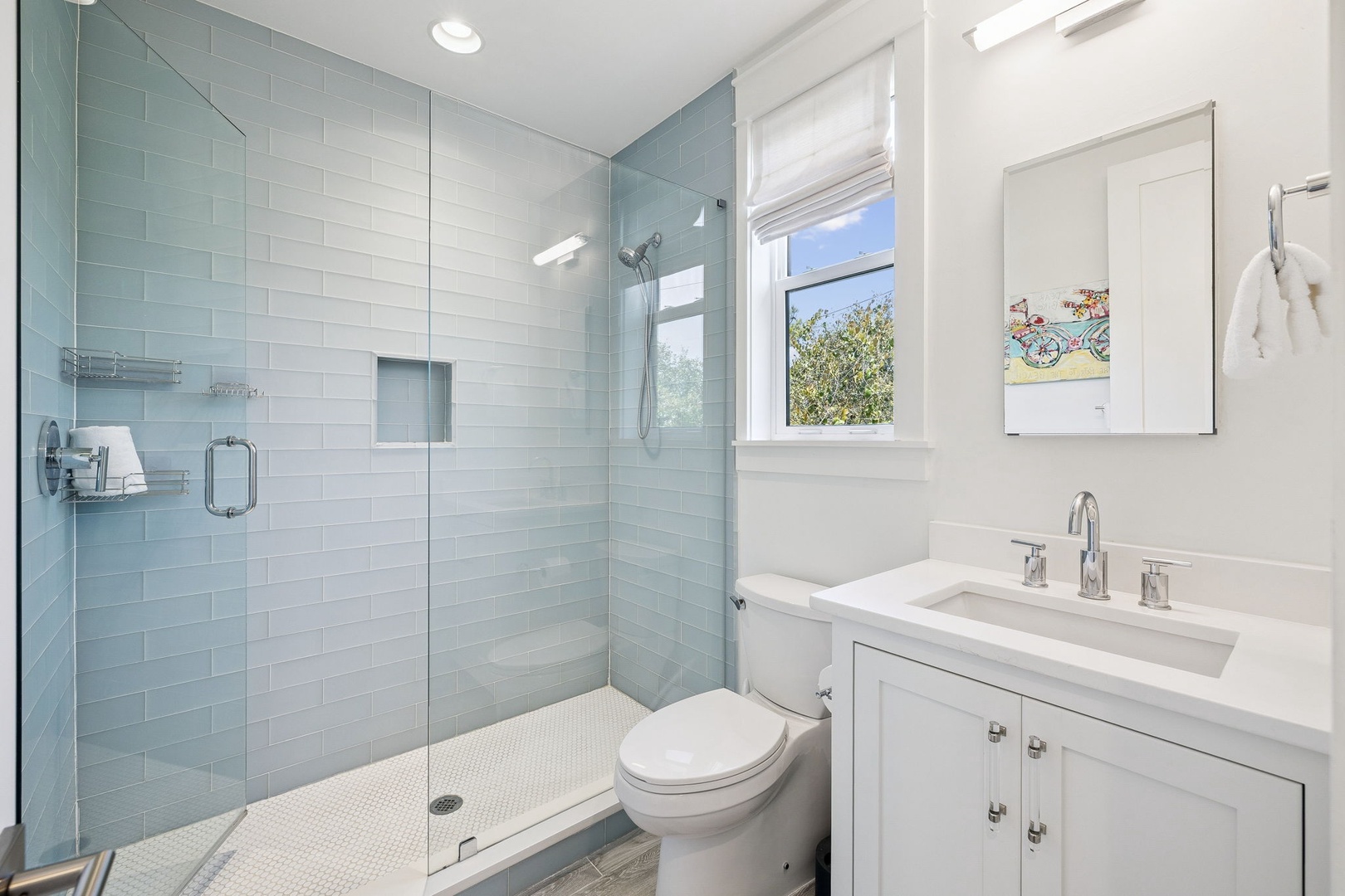 Unwind in your serene spa-style bathroom with calming blue tiles, spacious glass shower, and bright natural light.