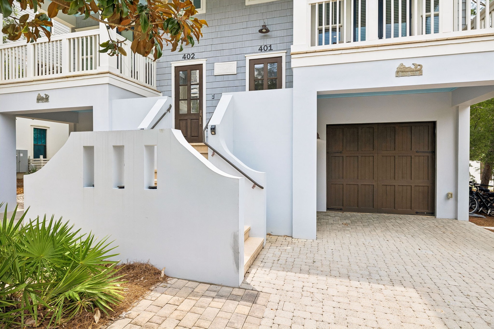 This welcoming beachside property entrance features charming coastal architecture with private entry stairways and convenient parking, just steps from the shore.
