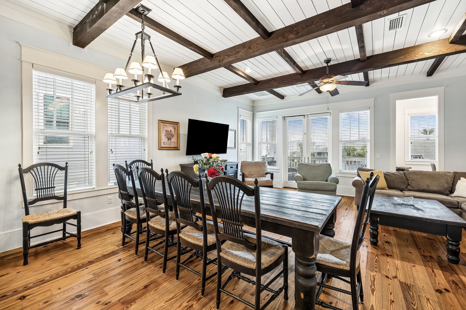 Gather around the farmhouse table in this bright, open space where rustic beams meet coastal charm—perfect for shared meals and laughter with your group.