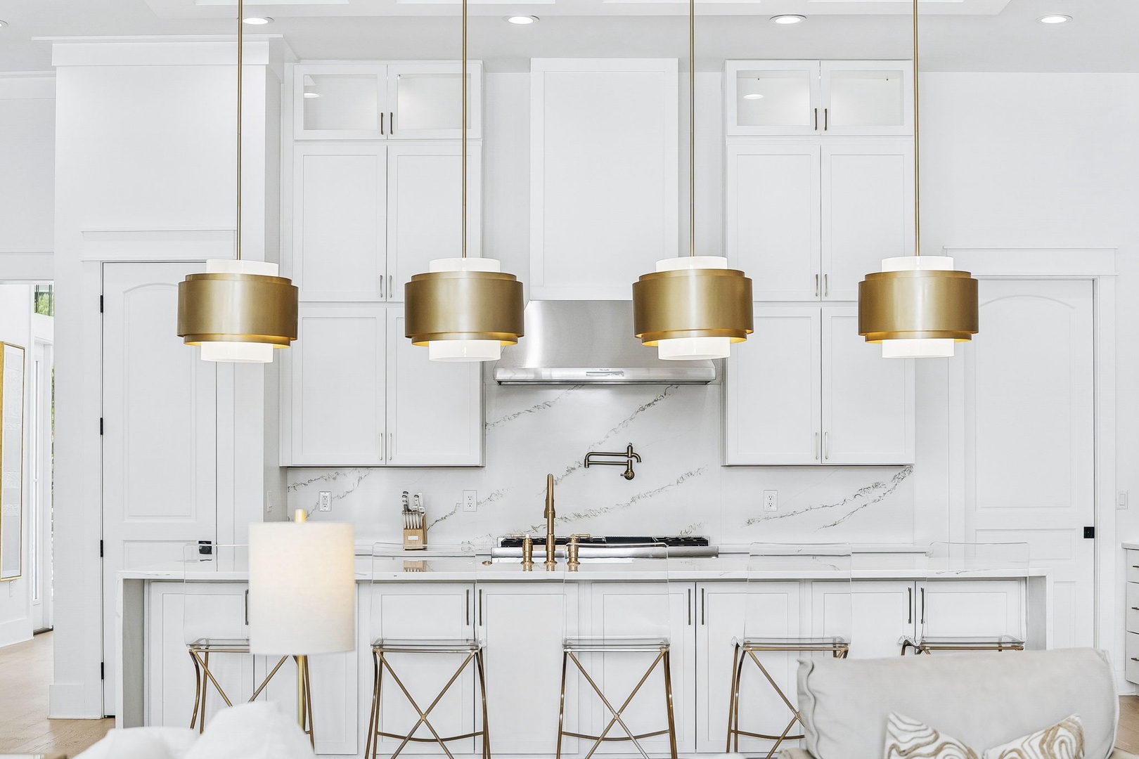 Step into this stunning white kitchen with gleaming marble backsplash, modern gold pendant lights, and a spacious island perfect for your morning coffee or evening gatherings.