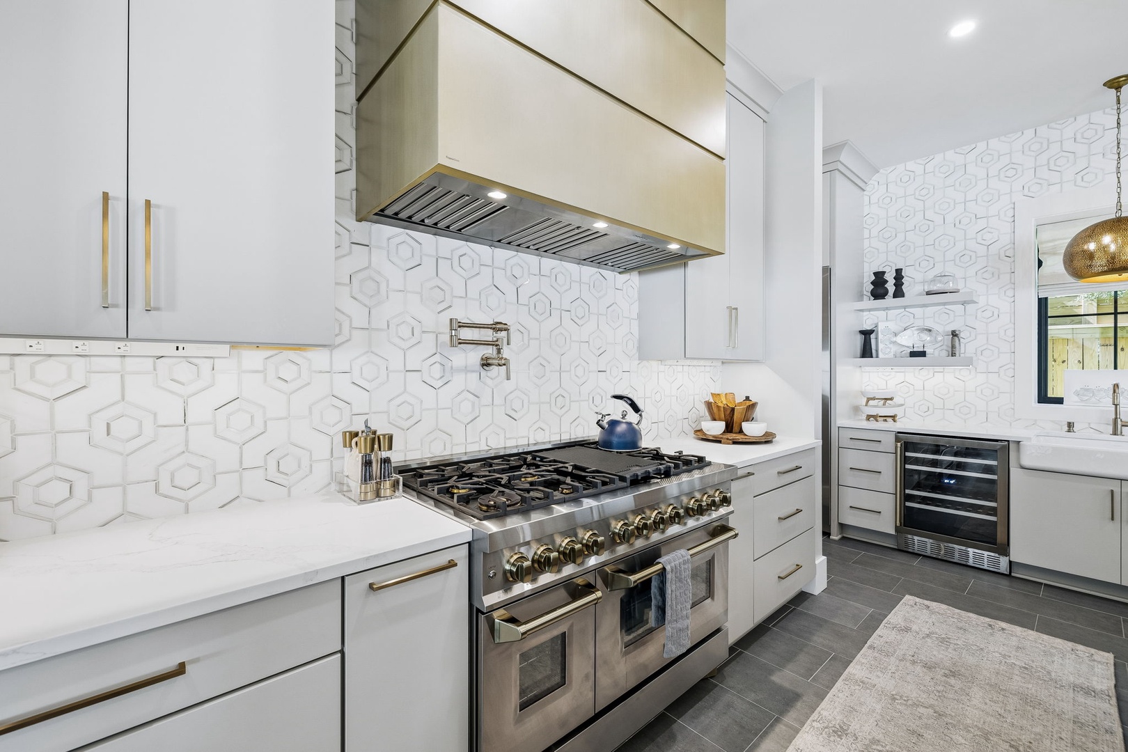 Your gourmet kitchen gleams with professional-grade appliances and designer details. Cook memorable meals on the dual-oven gas range beneath sleek ventilation, surrounded by pristine white cabinetry and elegant geometric tile.