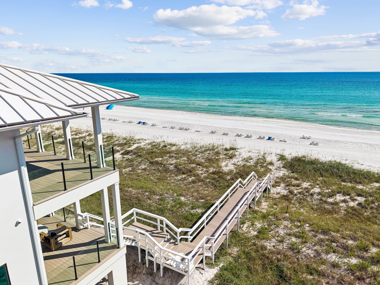 The property offers direct beach access via a private walkway, leading to pristine white sand and stunning turquoise waters, with a spacious balcony overlooking this coastal paradise.