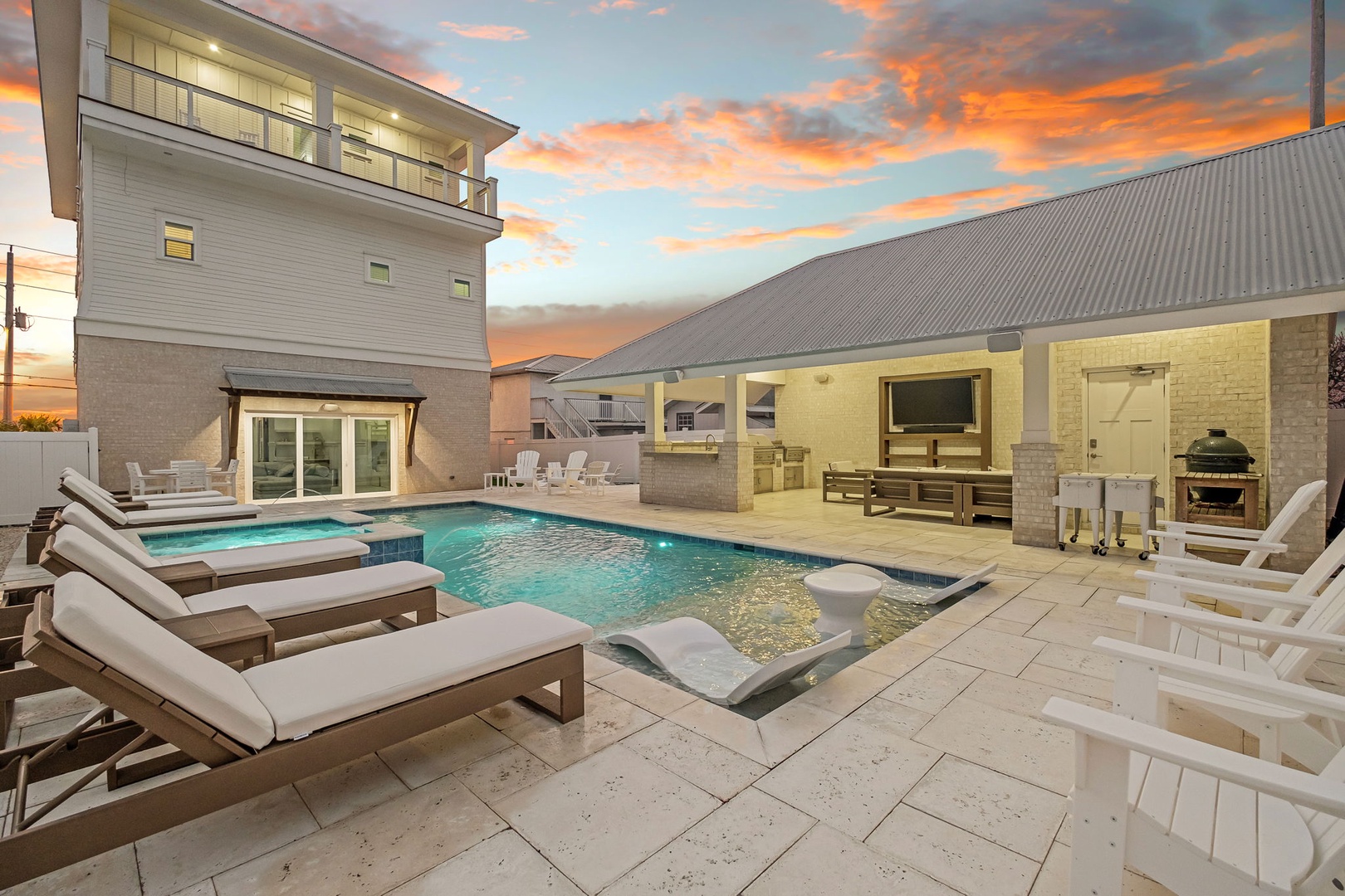 Your private oasis awaits with a sparkling pool, outdoor kitchen, and cozy lounge chairs under a stunning sunset sky.