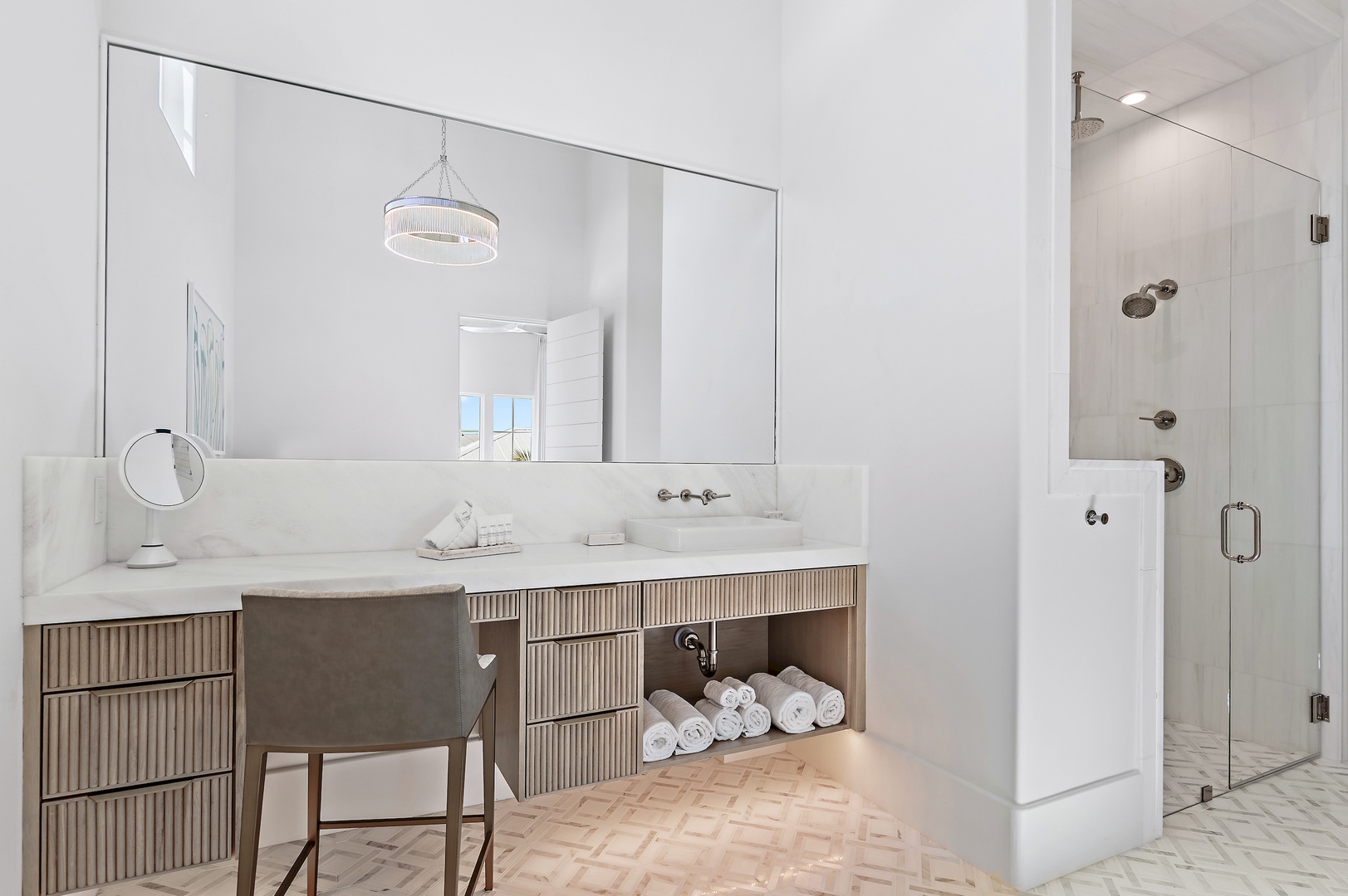 Step into your serene, spa-like bathroom with elegant marble countertops, a spacious glass-enclosed shower, and plush rolled towels awaiting your arrival.