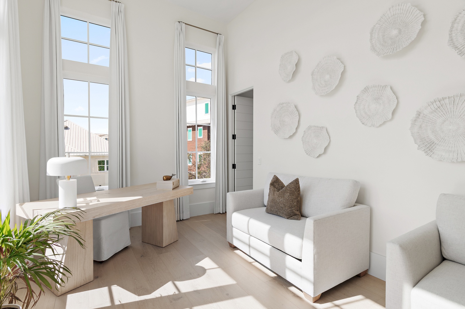 Bask in natural light streaming through tall windows in your serene living space, where coastal-inspired décor and plush seating invite you to unwind in effortless style.