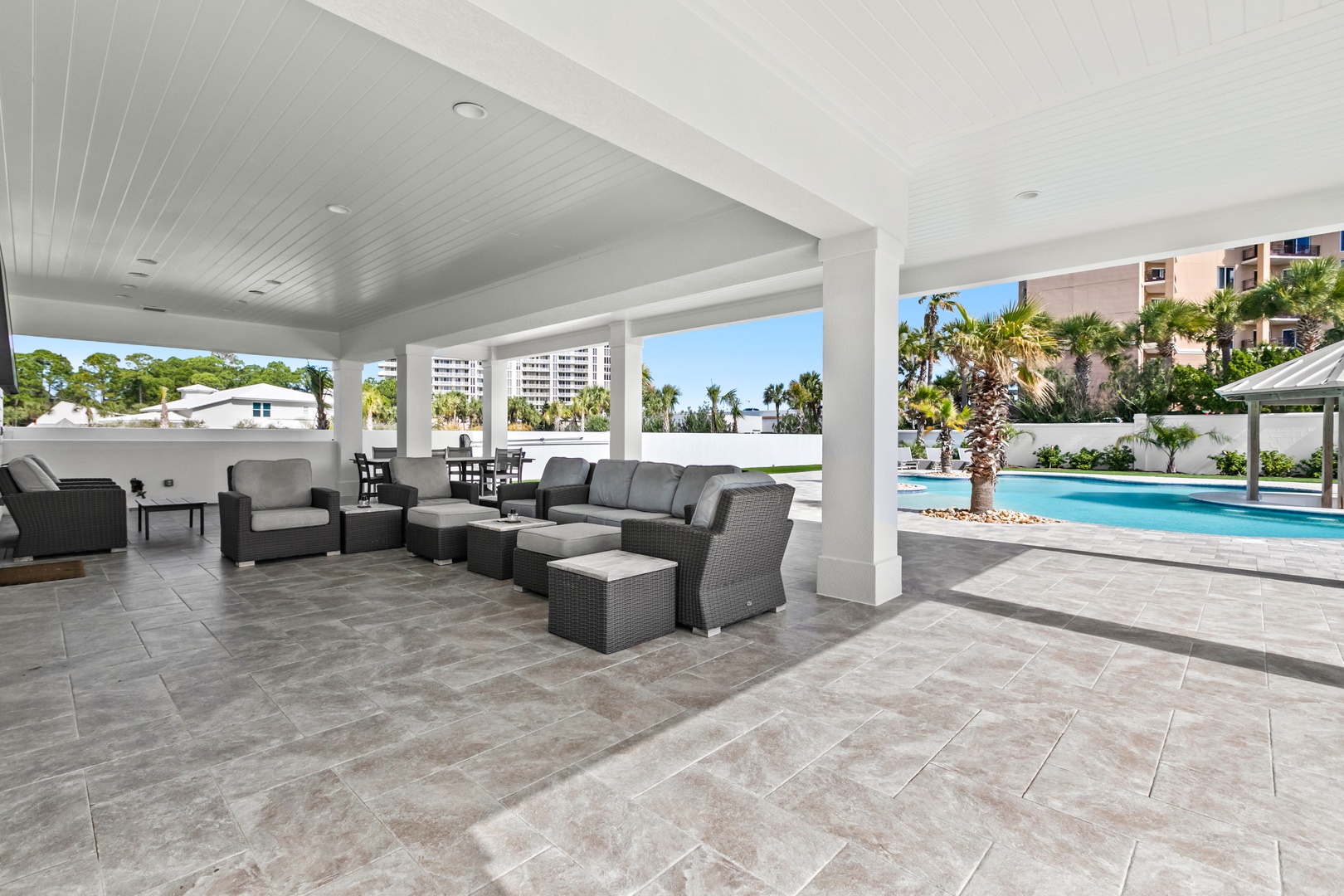 Unwind in your covered outdoor lounge with poolside views, perfect for lazy afternoons or evening gatherings under swaying palms.